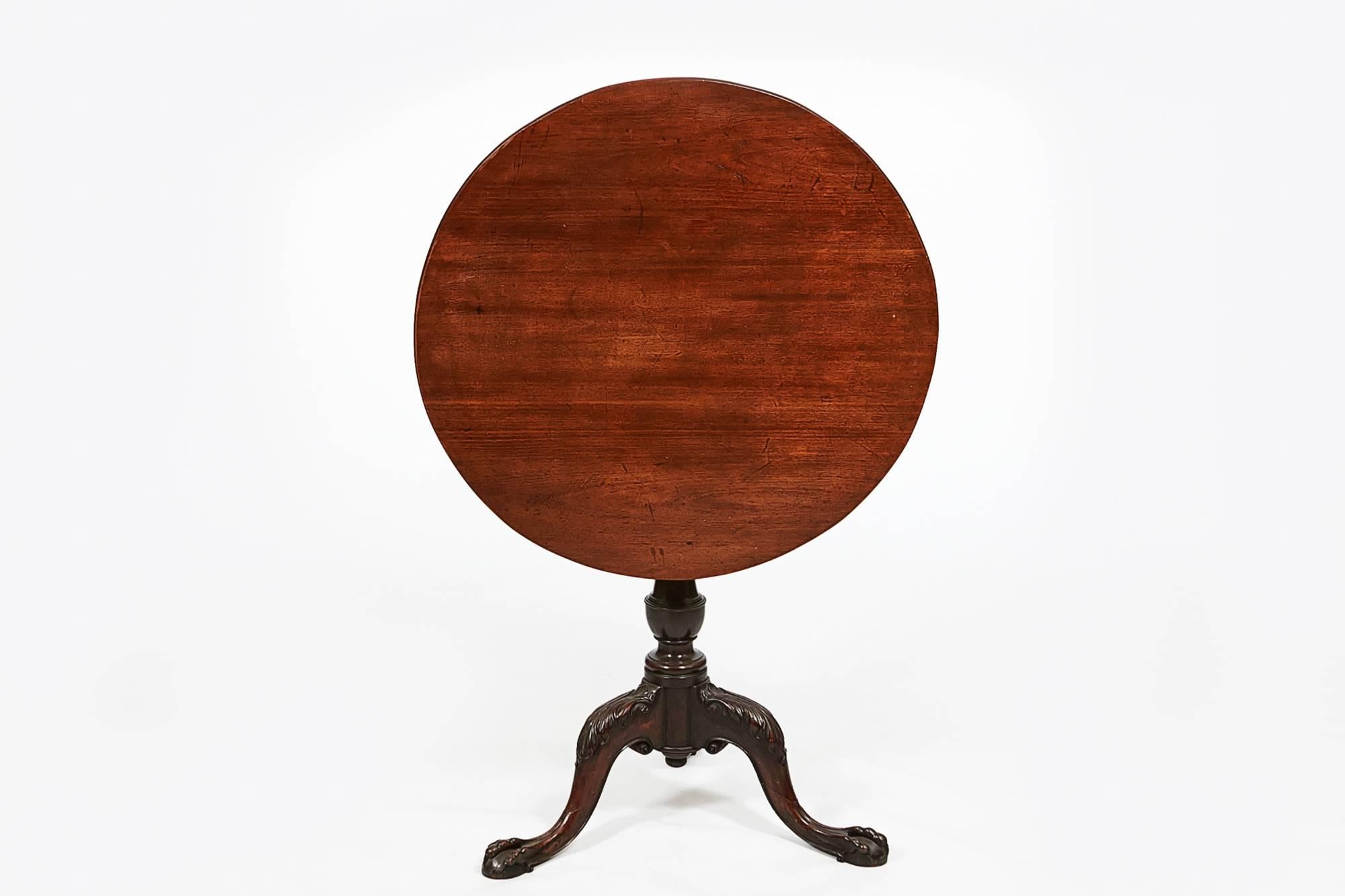 18th century George III mahogany circular tip up table on tripod base. The circular top on a turned pod, carved with acanthus leaves on the knee terminating in claw and ball feet.