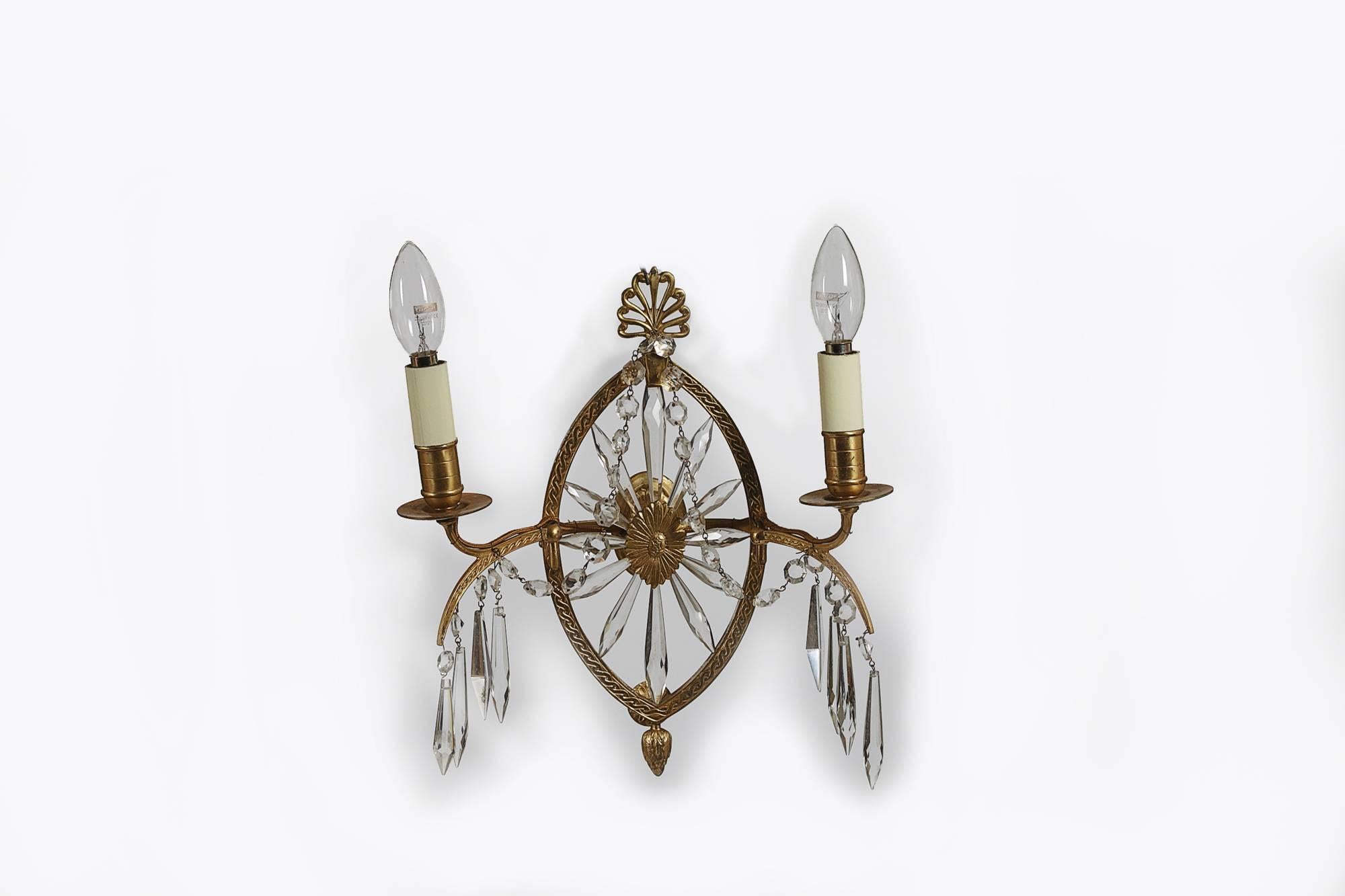 Early 19th century Regency set of four glass and gilt metal wall lights, electrified. Each central frame surrounding a glass sunburst, with an anthemion crown and acorn finial, with pairs of arms and glass drops.