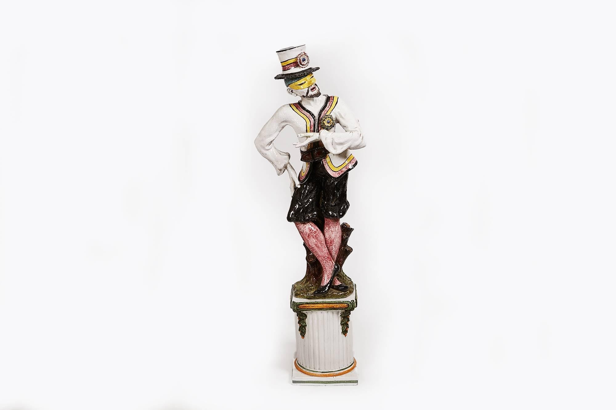 19th century pair of large ceramic painted statues on plinths, dressed as harlequins in a carnival style. One male and one female.