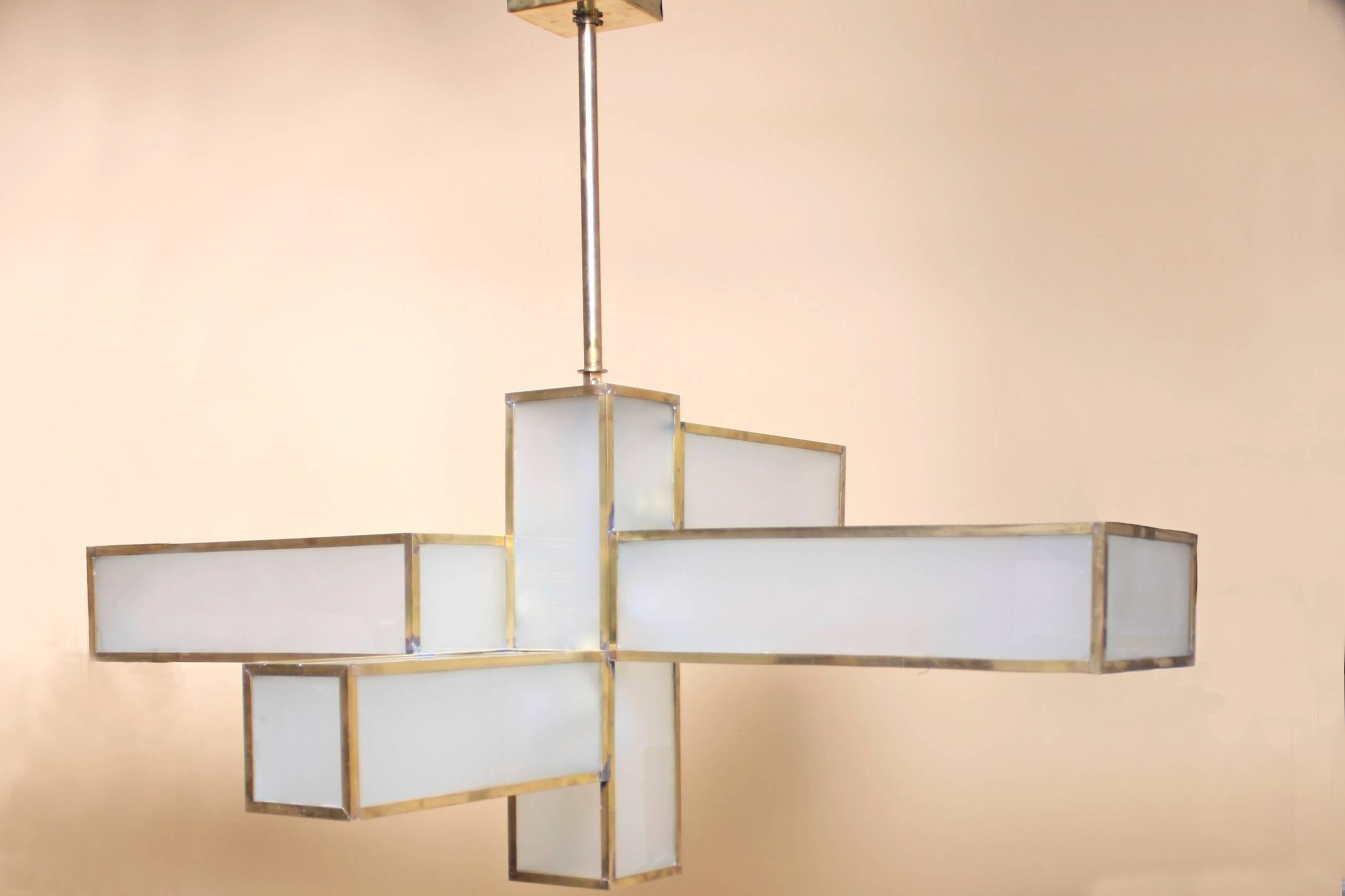 A large-scale, gorgeous chandelier made from opaque glass, forged brass and perforated brass shades along the bottom of the fixture. The fixture takes on a different shape depending on the angle from which it is viewed. Truly spectacular. Found in
