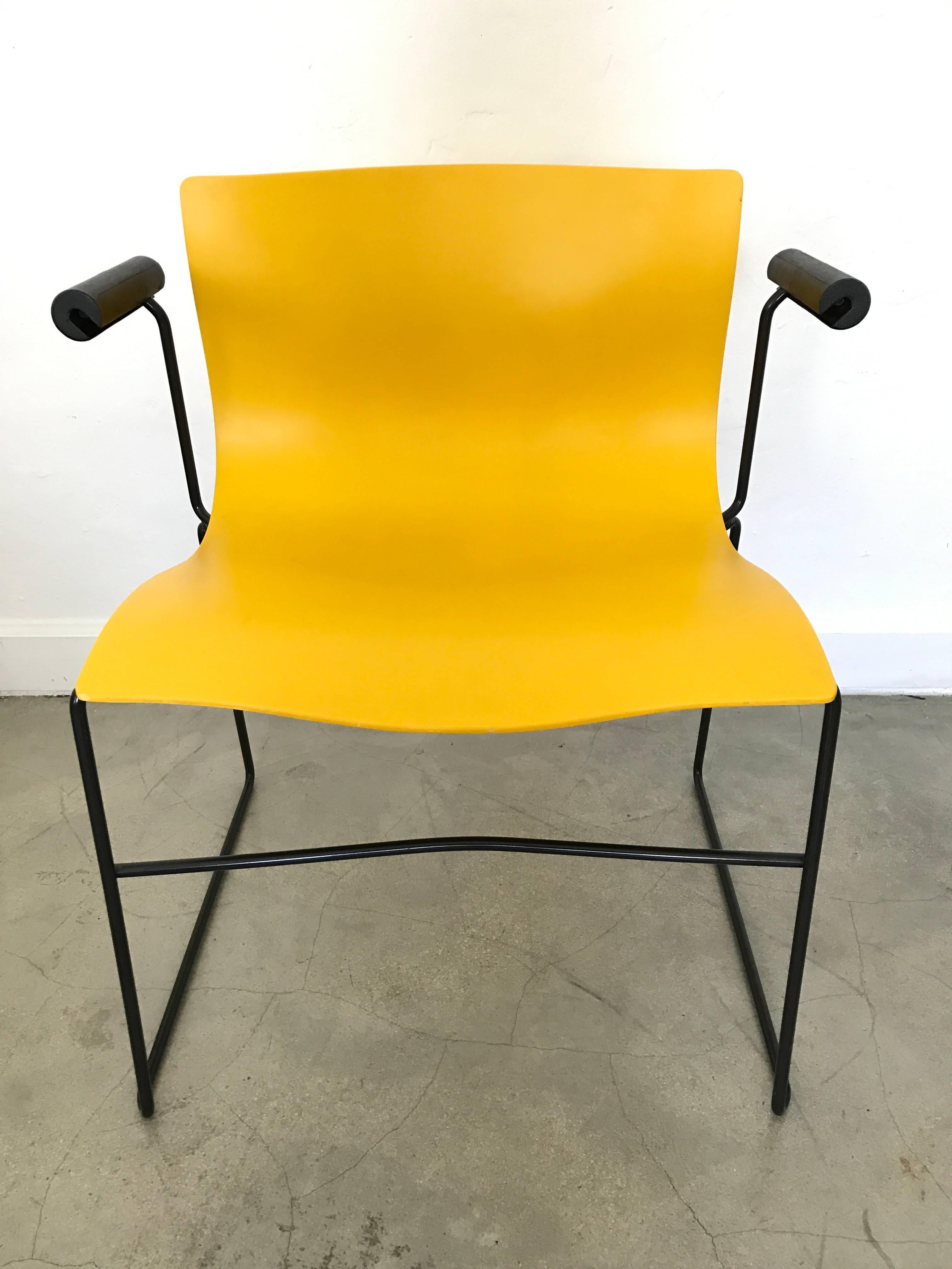 Four bright yellow sculpted dining or office chairs on a black enameled steel frame with cushion armrests by Lella and Massimo Vignelli for Knoll.