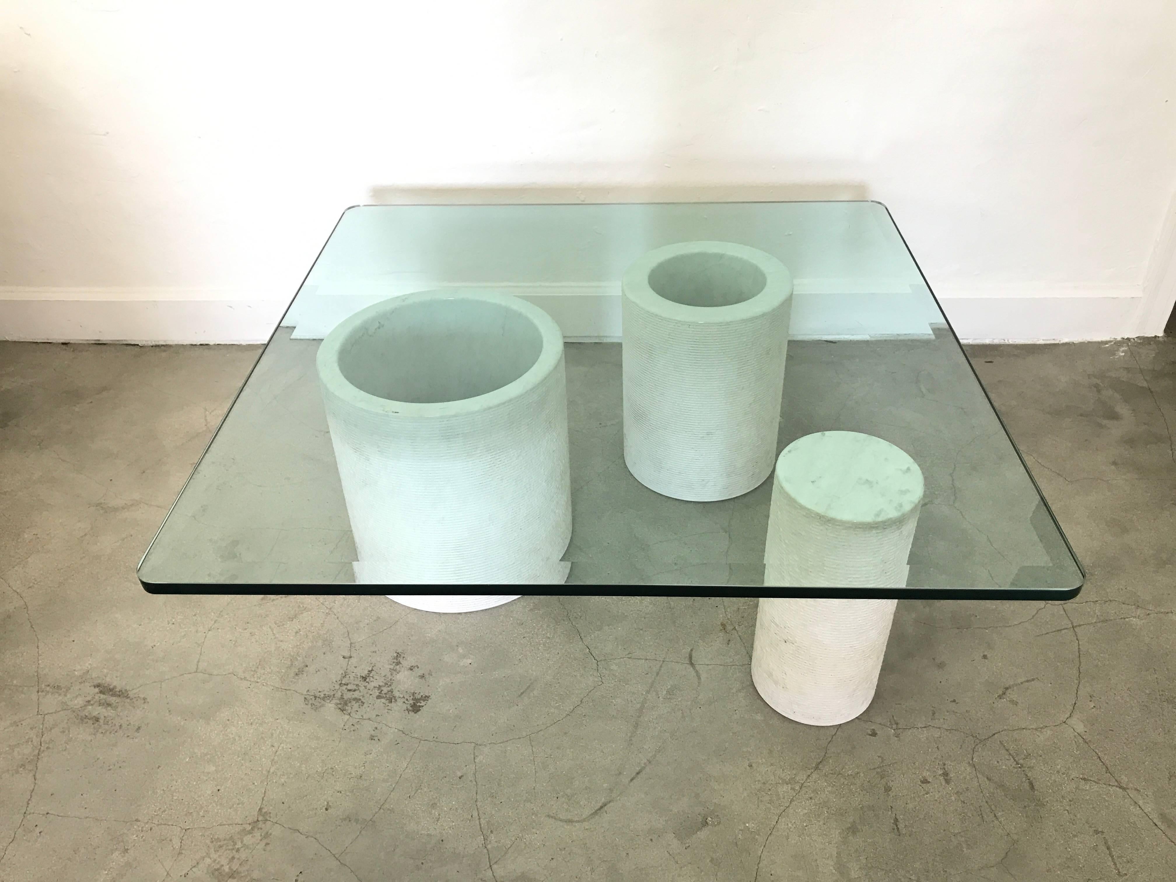 Carrara marble and half inch, beveled glass top coffee or cocktail table, Italy. Marble has a smooth, polished finish on top and inside the cylinders and the marble is etched on the exterior, style of Mangiarotti, model Loico.