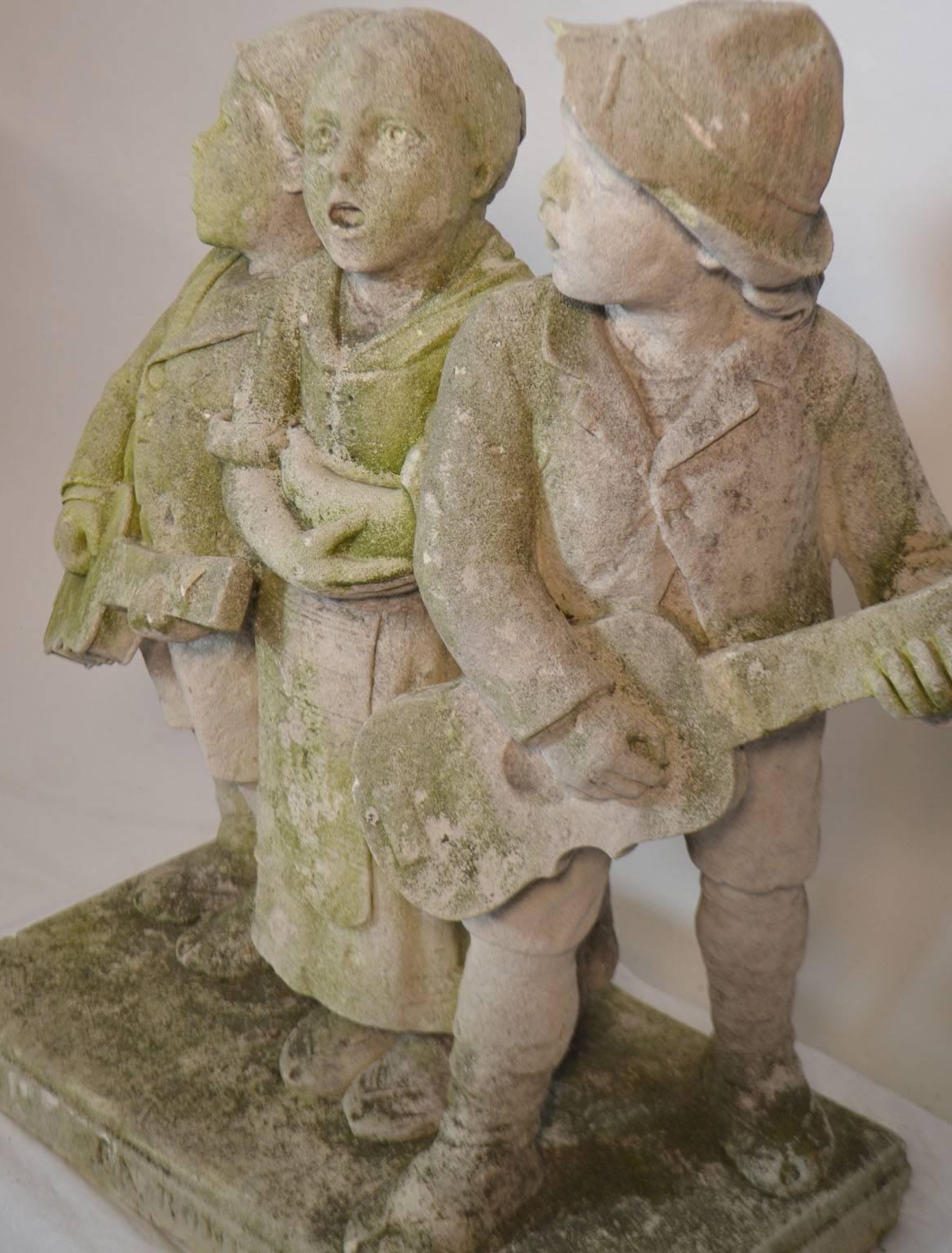 Carved stone statue of children standing and singing, circa 1900-1920.