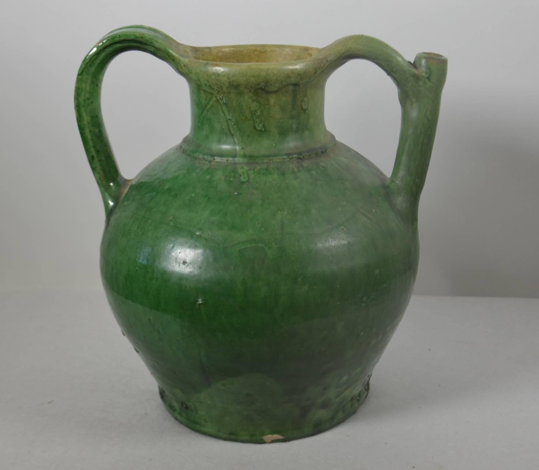 Terracotta jug with spout in handle, green glaze, circa 1860. Once a common piece of pottery used daily in French kitchens, these earthenware jugs have become showcase pieces sought by designers and collectors. These beautiful vessels offer a depth