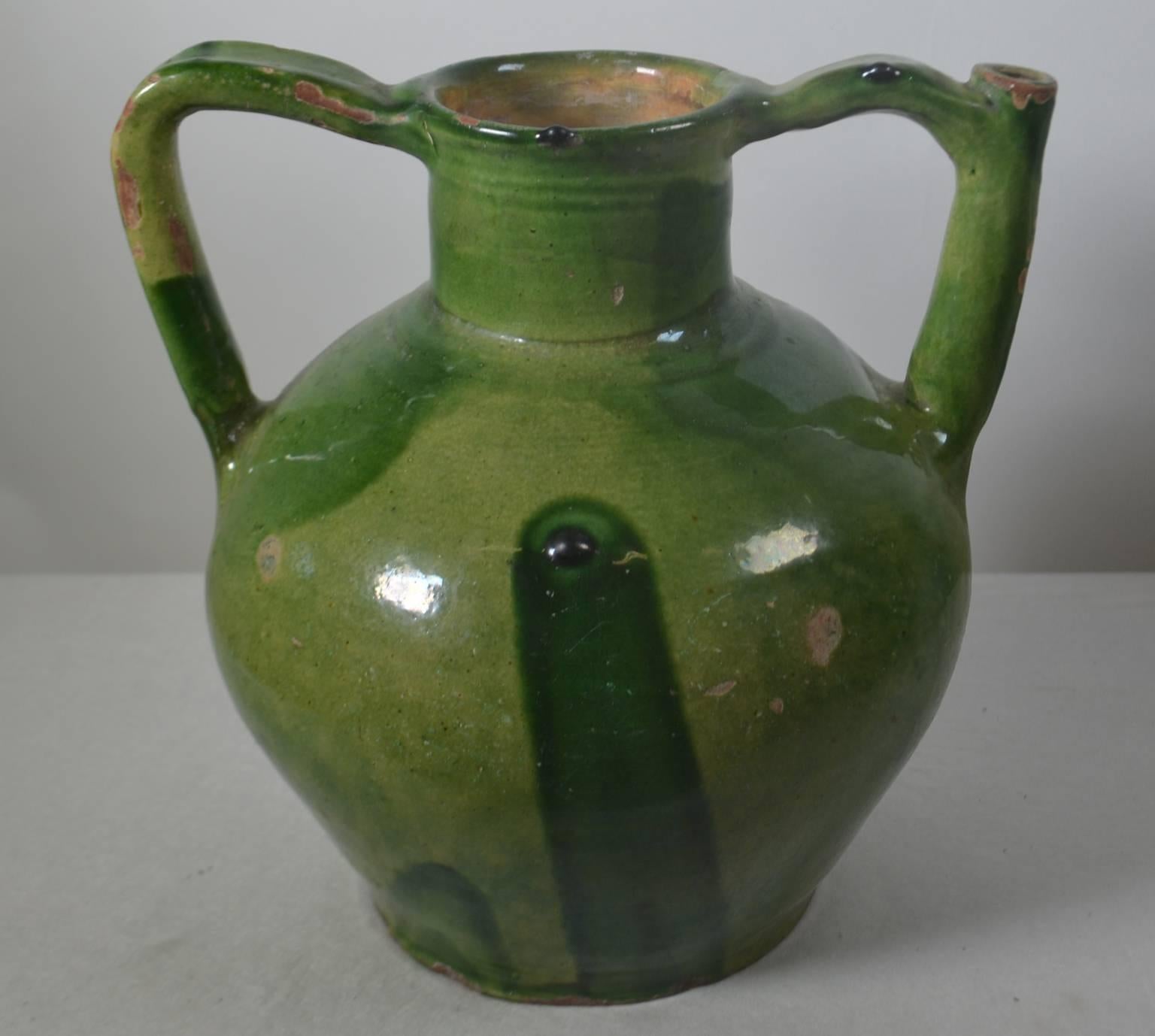 Terracotta jug with spout in handle. Green light and dark glaze, circa 1860. Once a common piece of pottery used daily in French kitchens, these earthenware jugs have become showcase pieces sought by designers and collectors. These beautiful vessels
