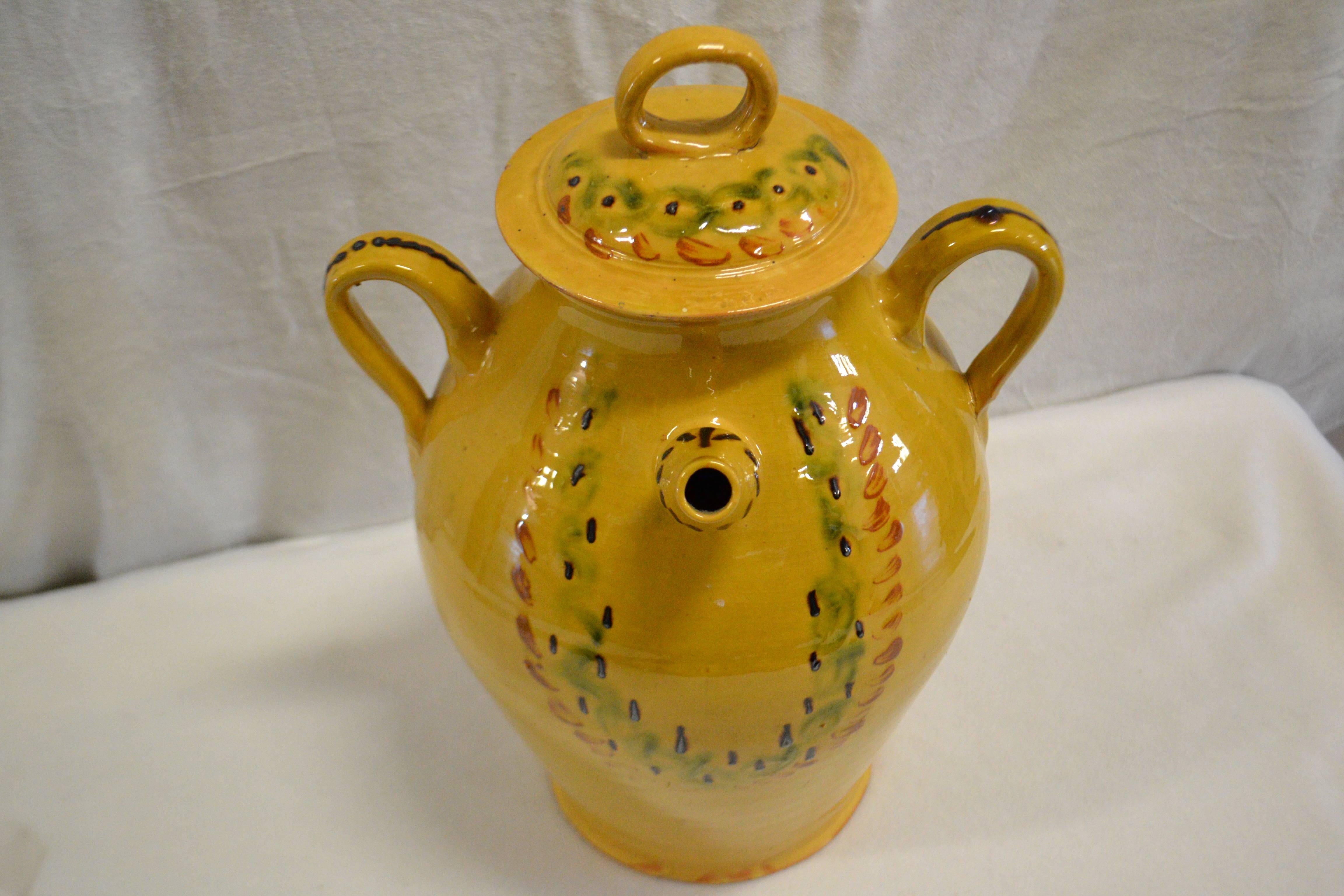 Turn of the century earthenware water jug with cream glaze and green and red finger style markings motif with handled lid and thin spout. Once a common piece of pottery used daily in French kitchens, these earthenware jugs have become showcase