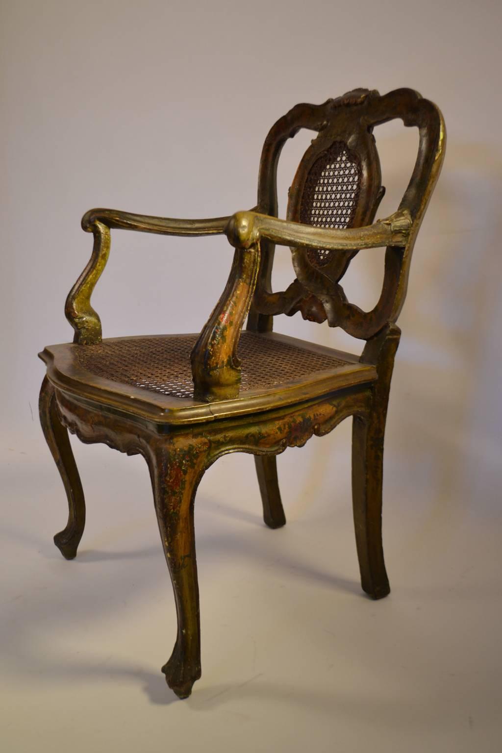 A Venetian carved and polychrome paint-decorated armchair, 18th century, molded crest rail, caned splat, shaped arms, caned seat, cabriole legs, shaped feet.