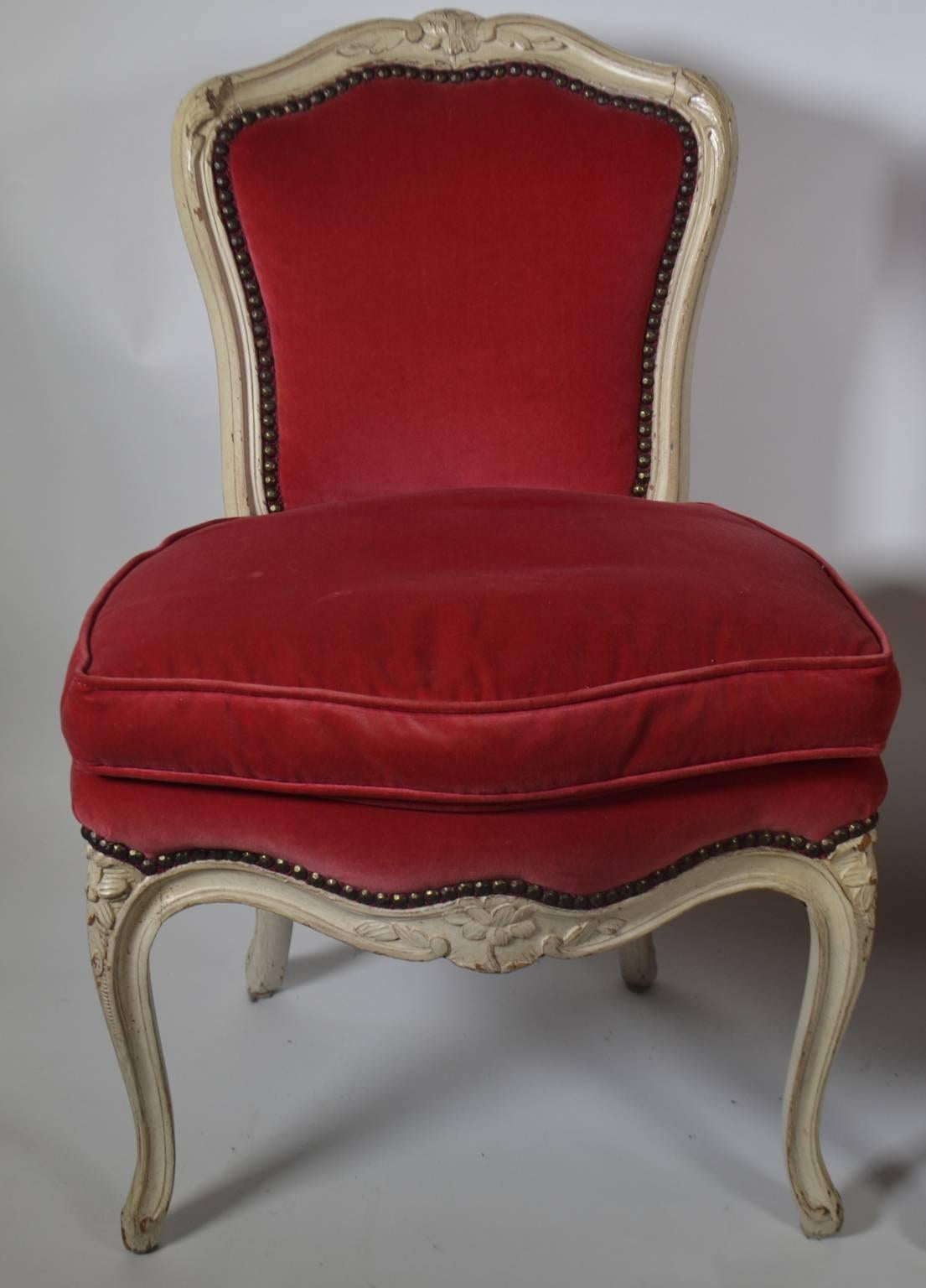 A pair of Louis XV-style carved and creme peinte upholstered chairs, shaped floral crest rail, padded back serpentine seat rail, cabriole legs. Measures: 18