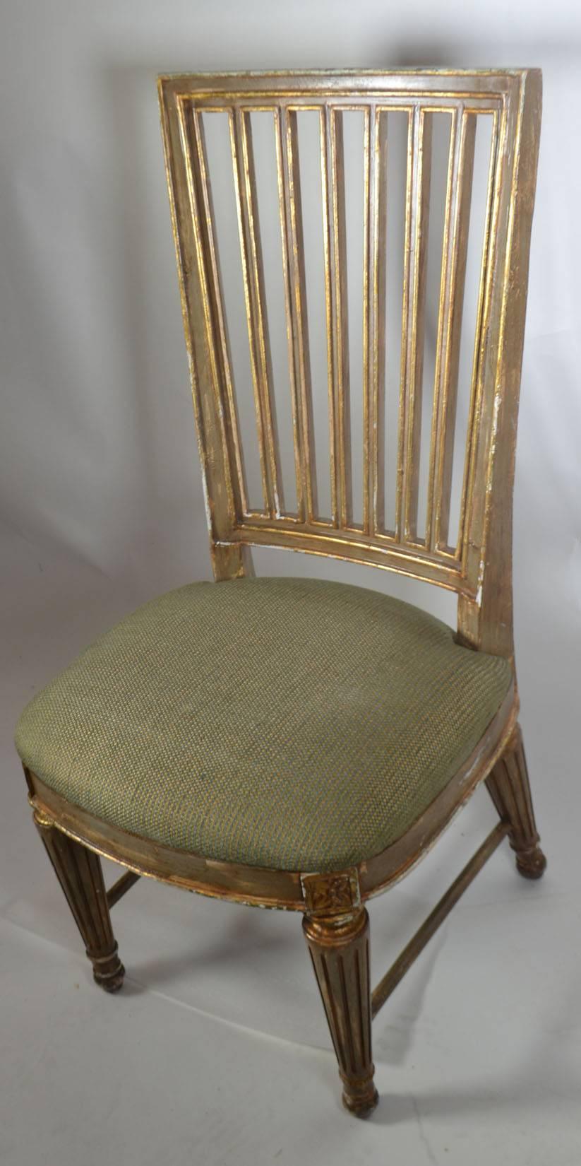 Suite of eight parcel-gilt and polychromed dining chairs, of Italian neoclassical inspiration, comprised of a pair of armchairs and six side chairs, each with a molded framed back with vertical slats, bowed seat and tapering fluted legs.