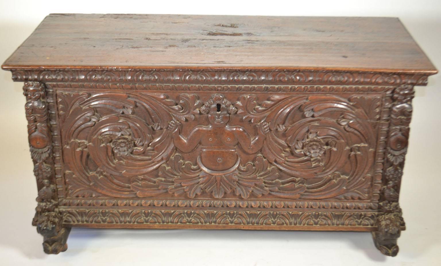 A continental carved walnut chest in the Renaissance taste, 18th century, probably Italian, the lid opens to a void interior. The case is carved with figures, acanthus scrolls and foliate moldings on anthropomorphic feet, casters.