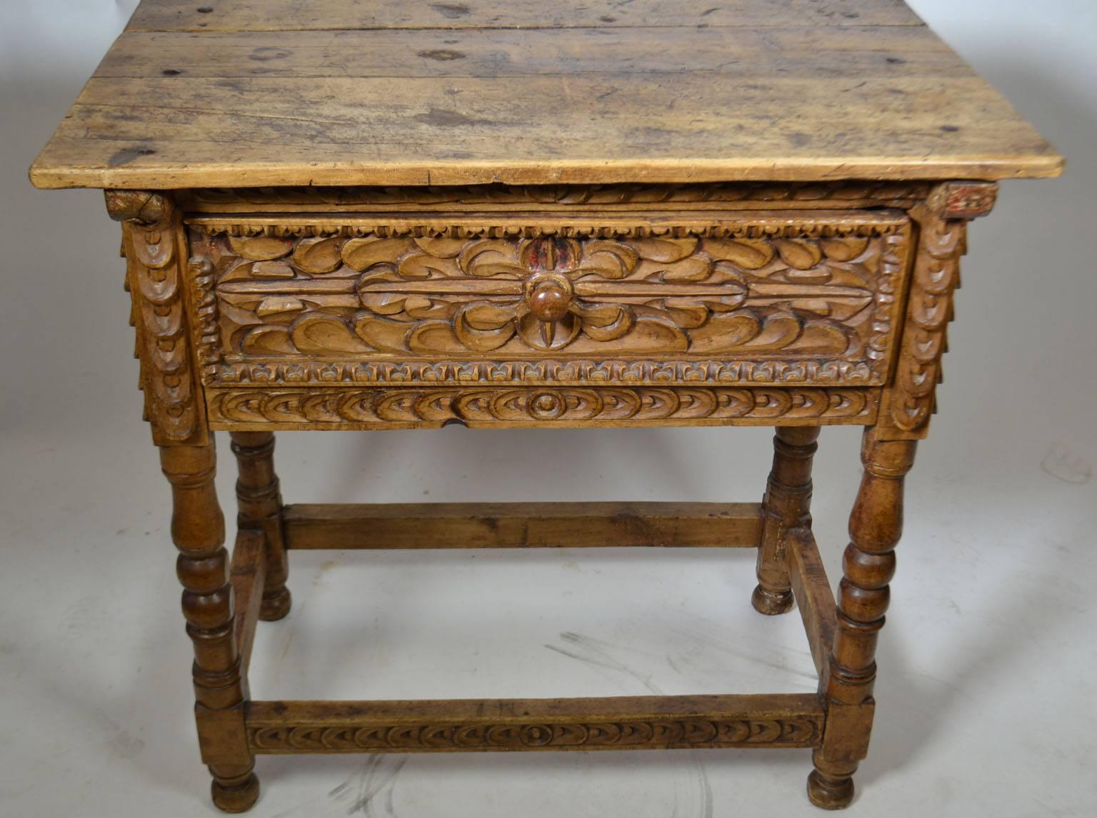 18th century Spanish Colonial side table with central drawer, turned legs, fish tail carving surrounding typical Spanish carved rosettes, a beautiful planked top, resting on an square stretcher and ball feet, Peru.