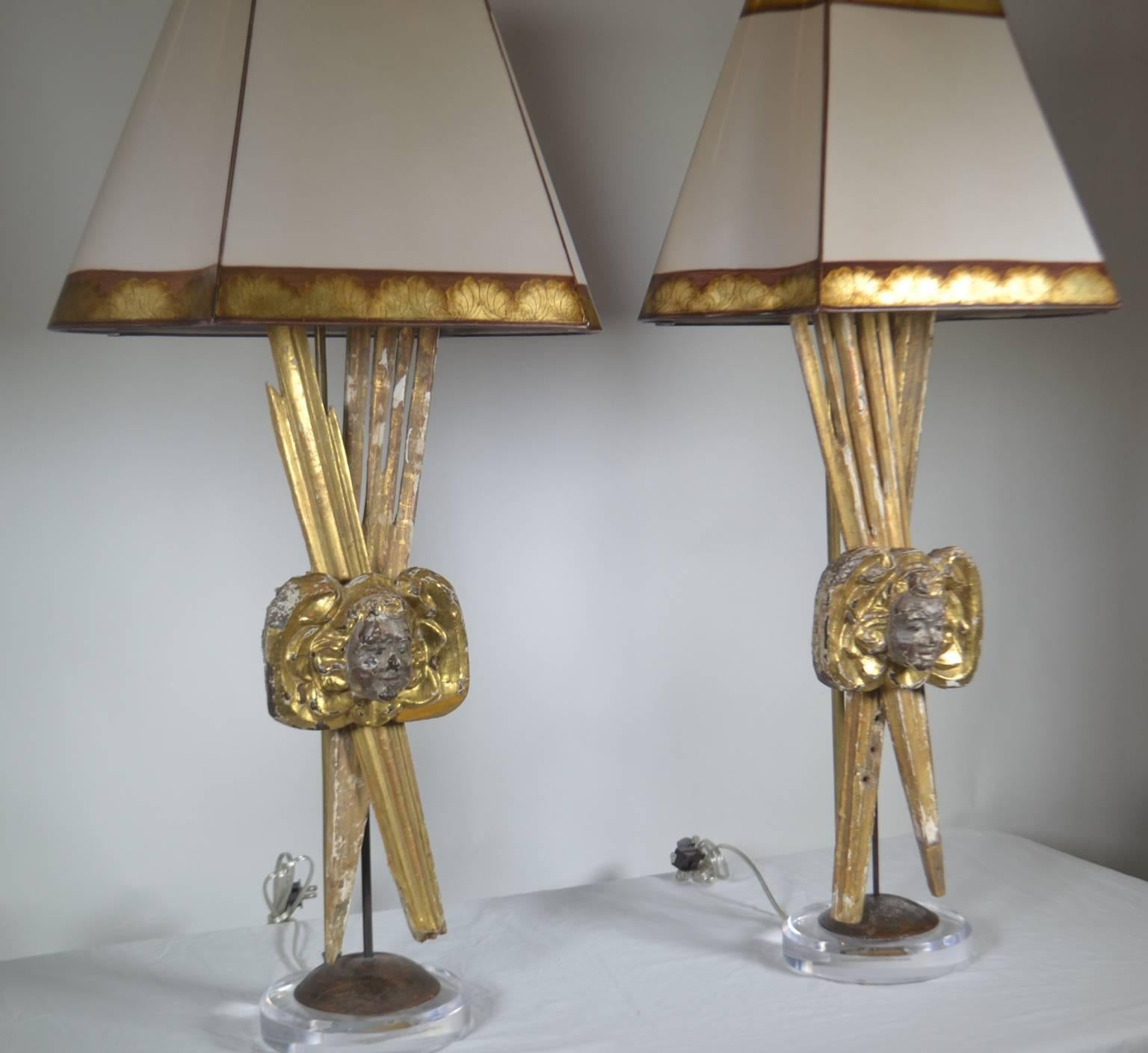 Paire de pièces italiennes en bois doré du XVIIIe siècle transformées en lampes avec des visages de putti et des rayons de soleil.