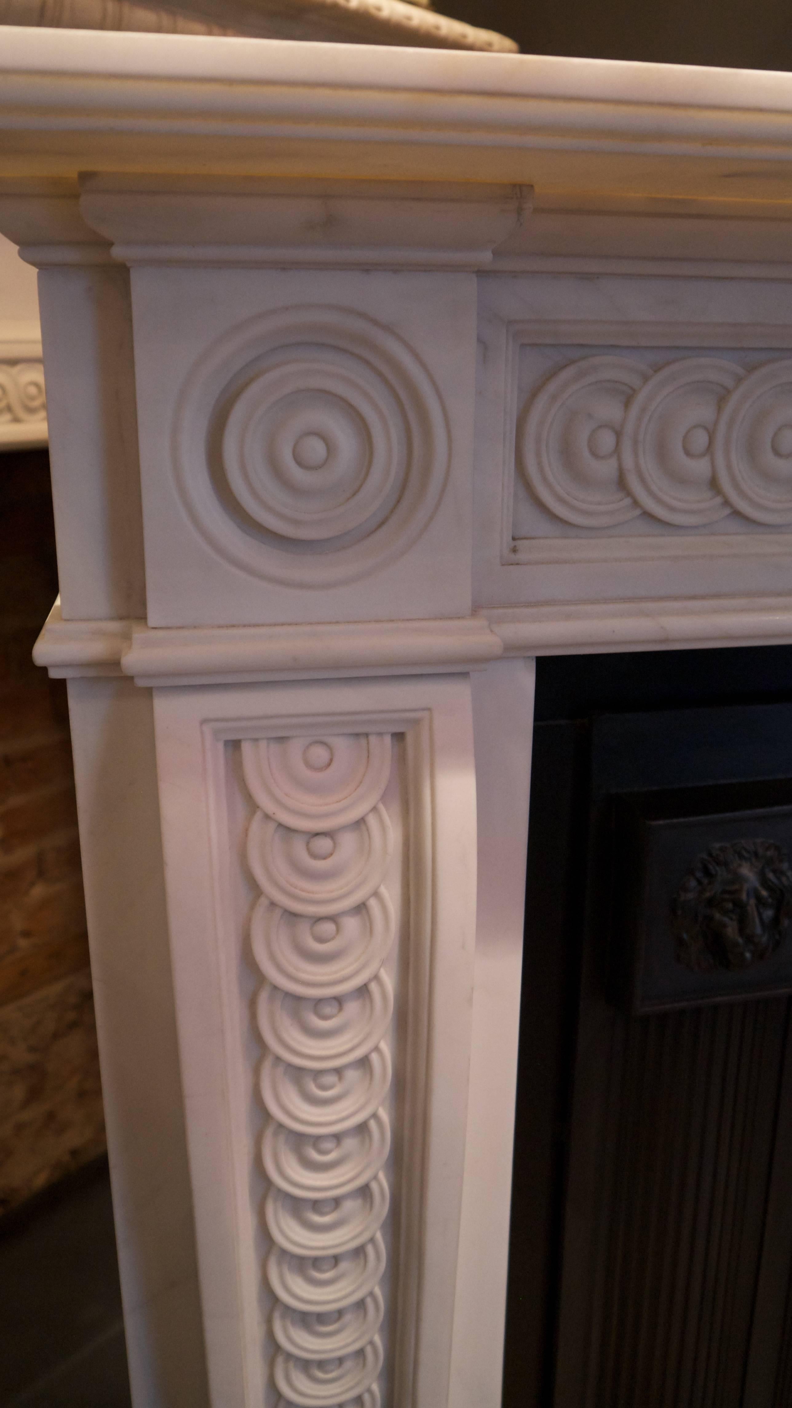 Reproduction Georgian style aged Statuary white marble mantel piece decorated with overlapping guilloche and bulls eye corner blocks. Opening size 40