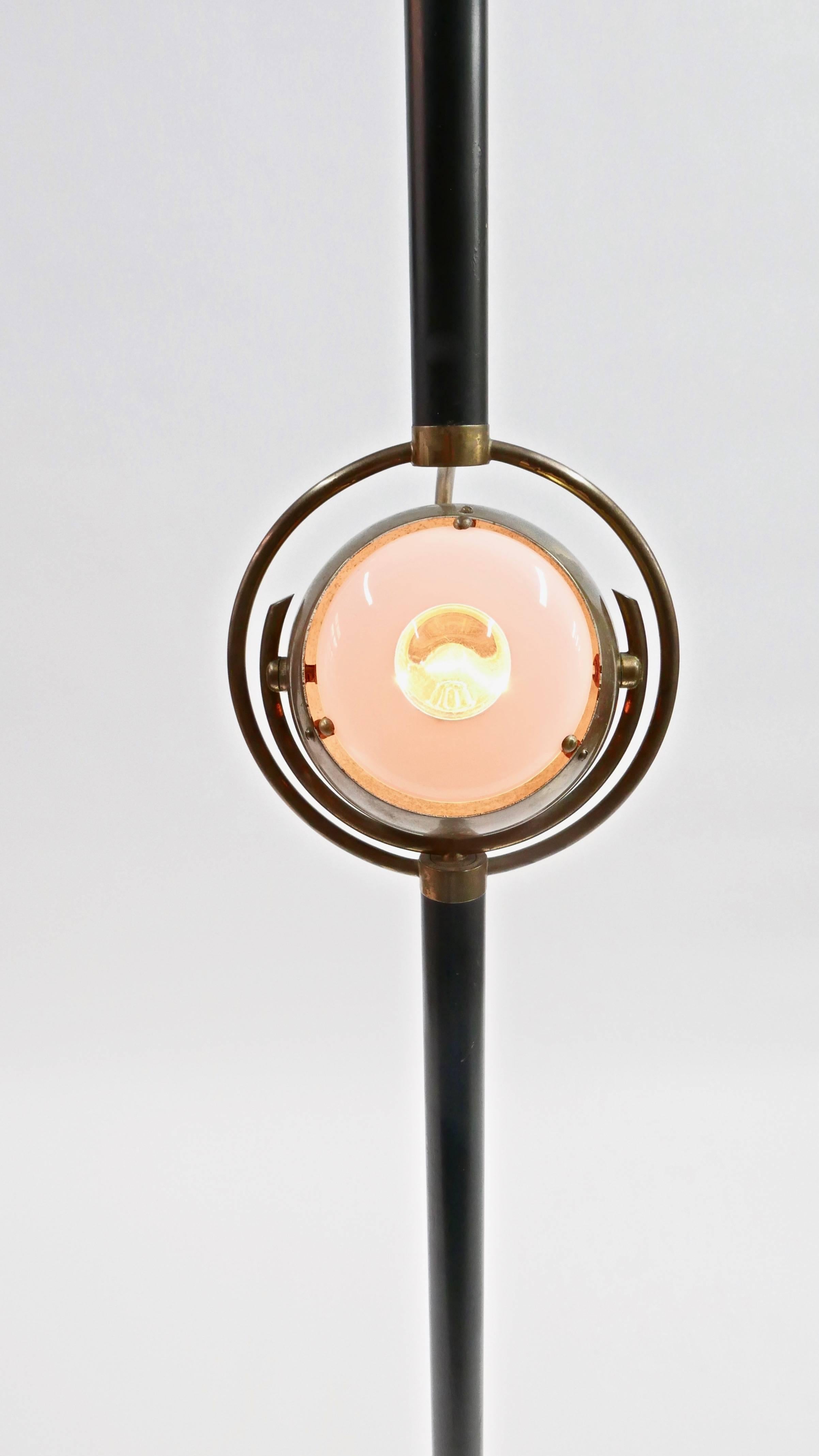 This sculptural design that features an eye shaped lens. The lamp illuminates up from the top shade and can be directed from the second lamp in the brass sphere.
 
