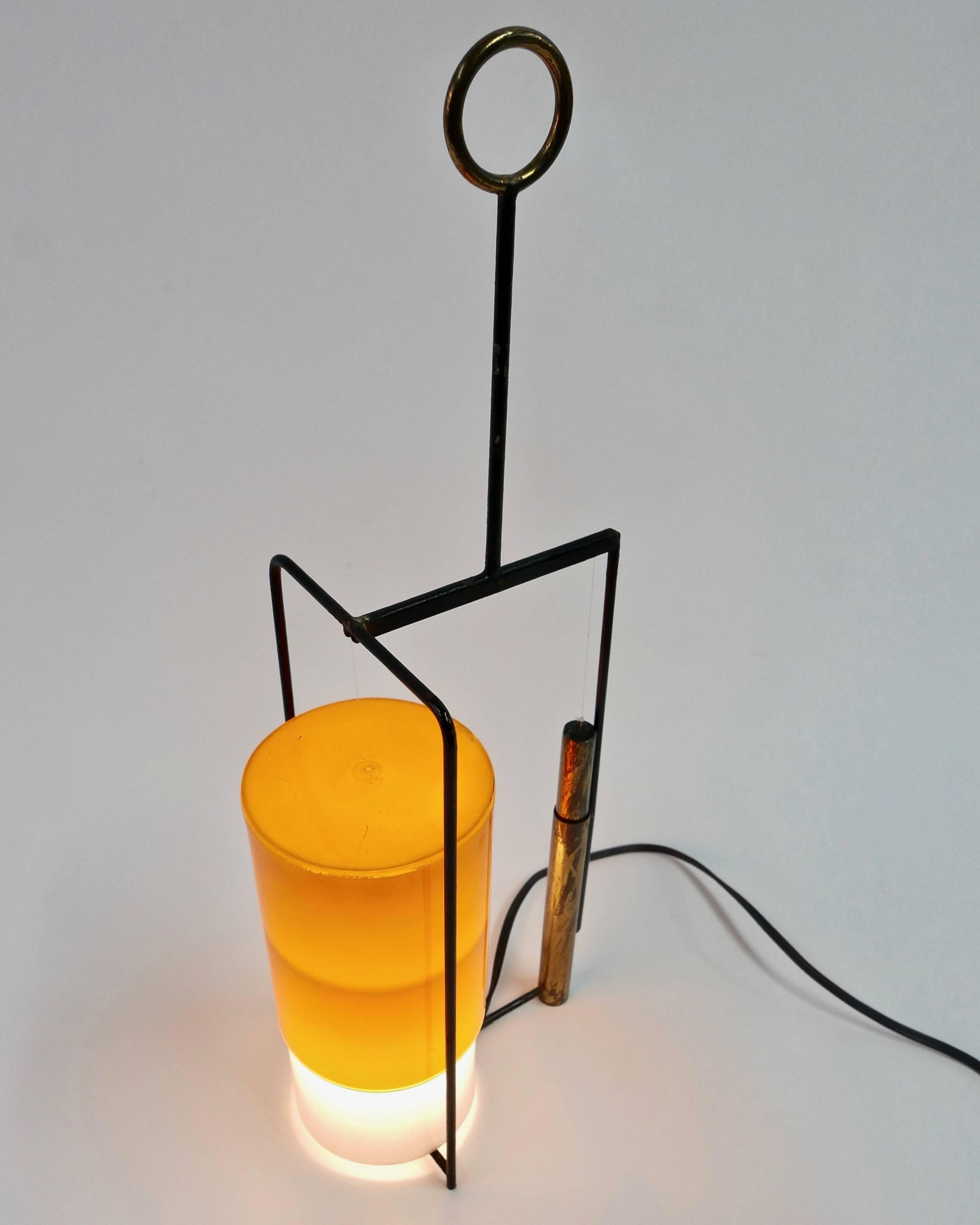 A small-scale table lamp with acrylic shade that adjusts up down with the aid of a brass counter weight.