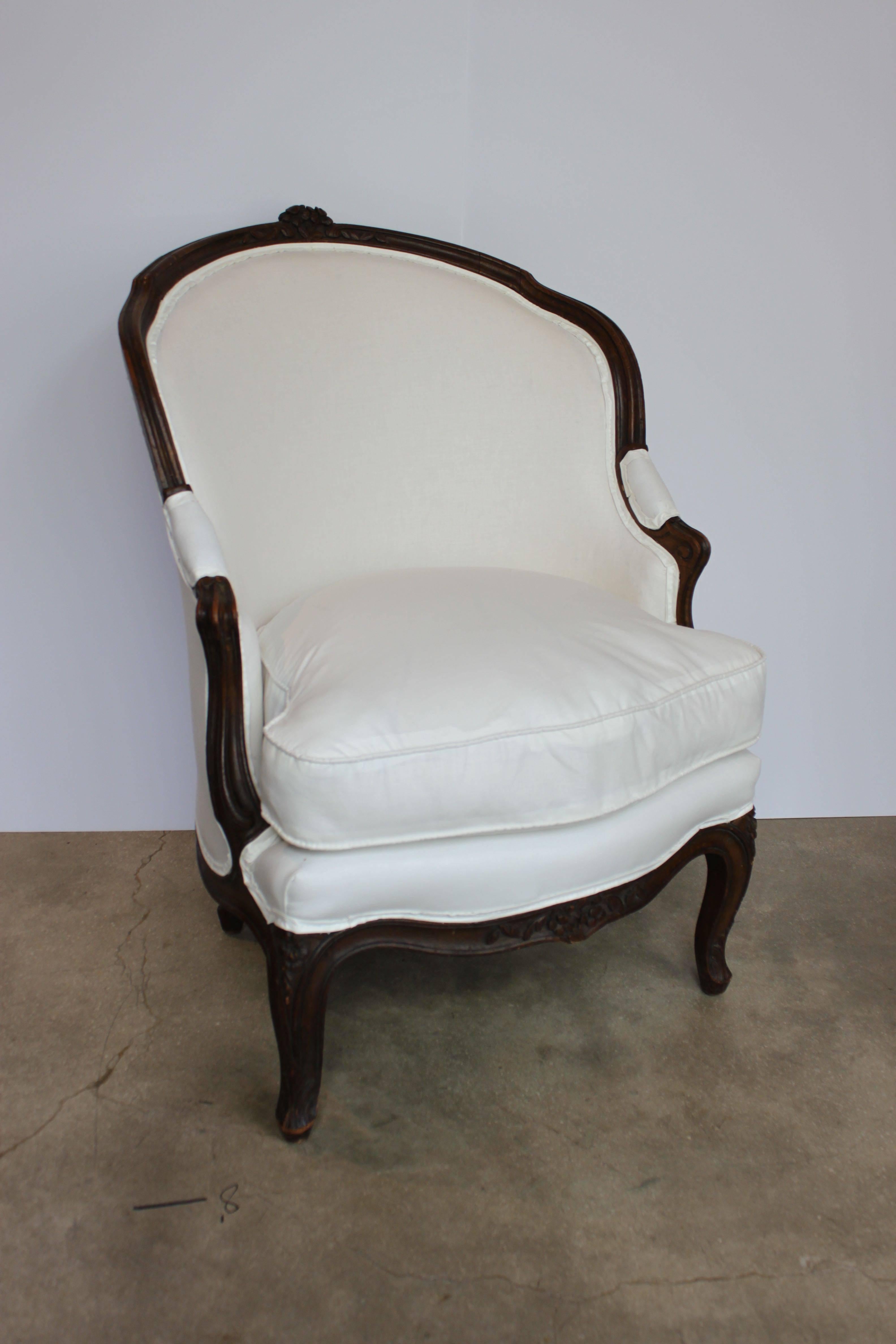Oval back dark walnut Louis XVI style carved wood bergere that has been newly-upholstered in muslin. The chair shows minor wear on the legs but is in sturdy condition, France, late 19th century.
