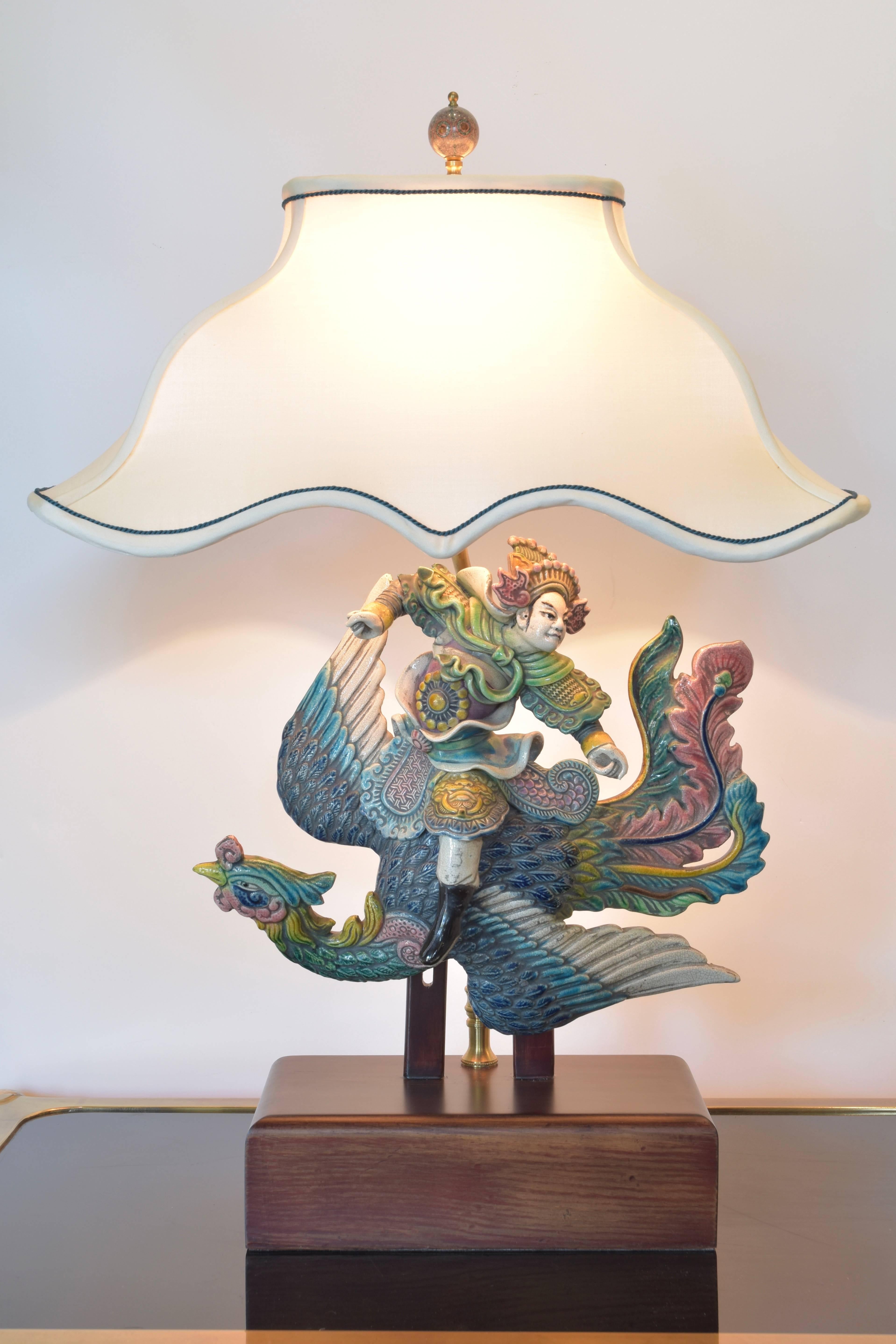 Whimsical Chinese roof tile depicting a warrior on a winged bird. A delightful piece with beautiful coloration in shades of aqua, blue, celadon, yellow and rose.  The custom silk shade perfectly follows the lines of the figure in flight.