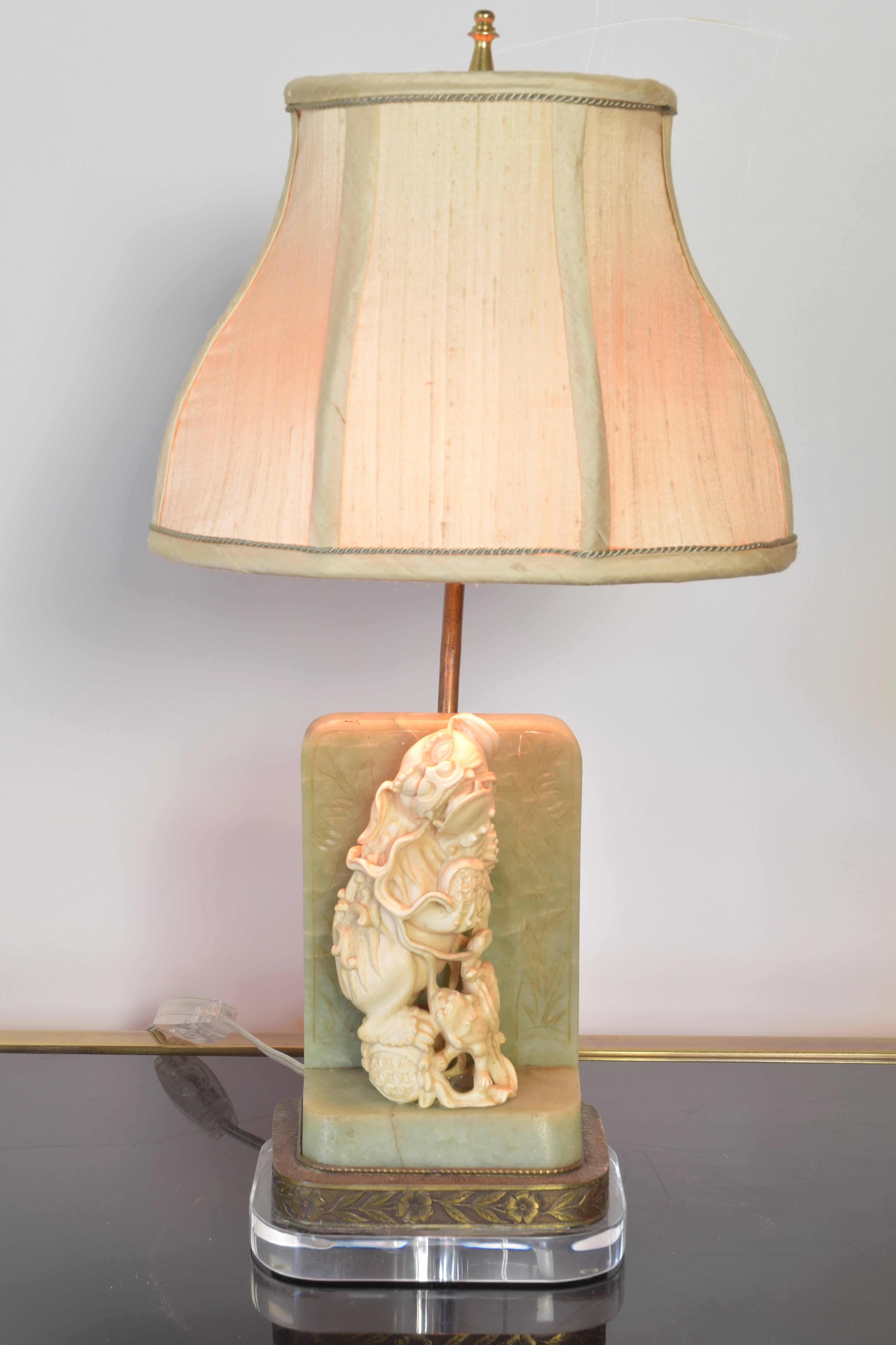 Charming antique carved foo dog mounted on a jade and bronze base.  Recently updated with a lucite plinth and new custom raw silk shade.  