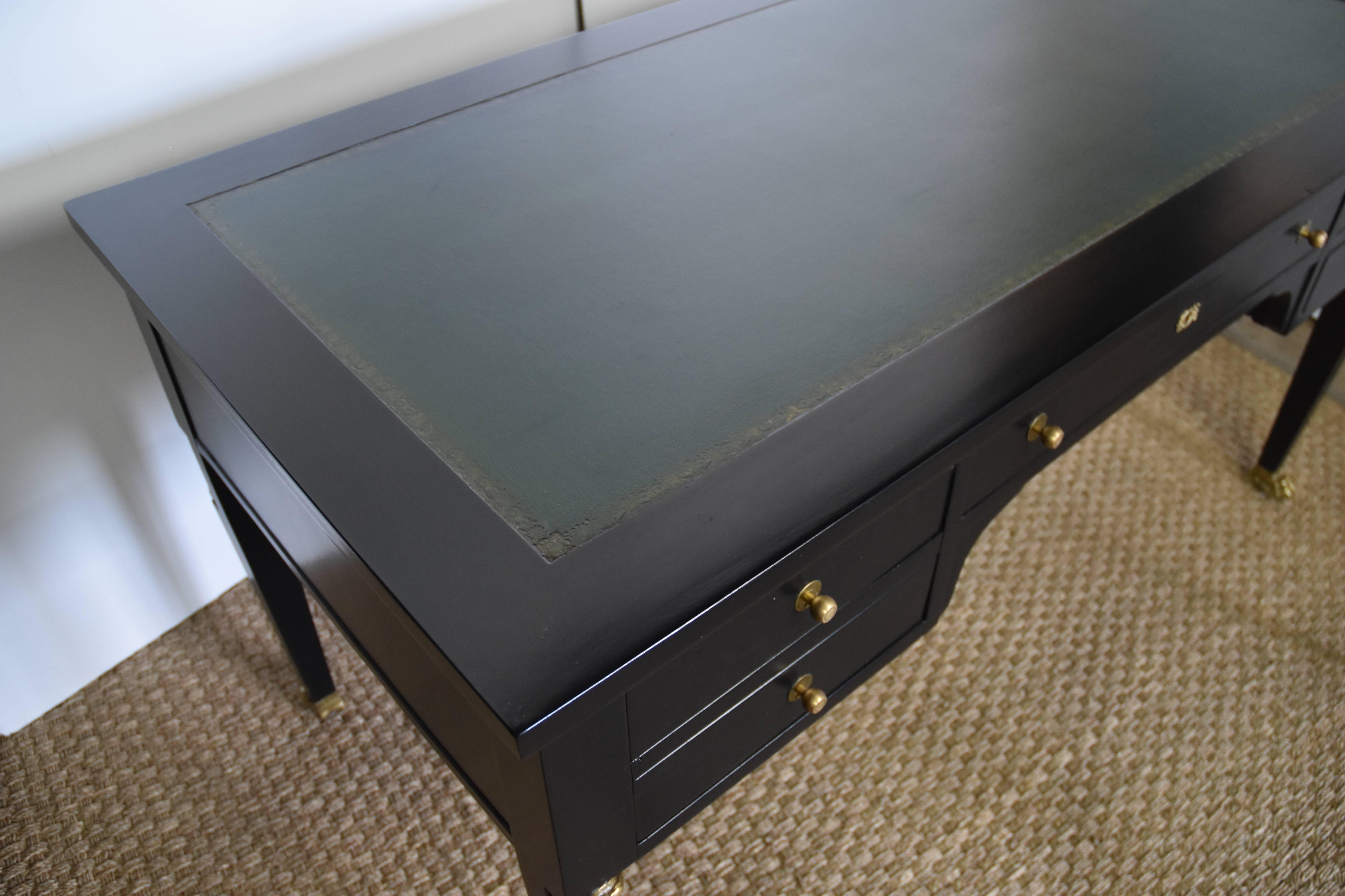 Lovely Empire style bureau plat with green top and painted black finish. The front of the desk features a pair of bronze busts and later added brass pulls. Each of the legs has paw feet. There are two pull-out extensions on each end. The desk is