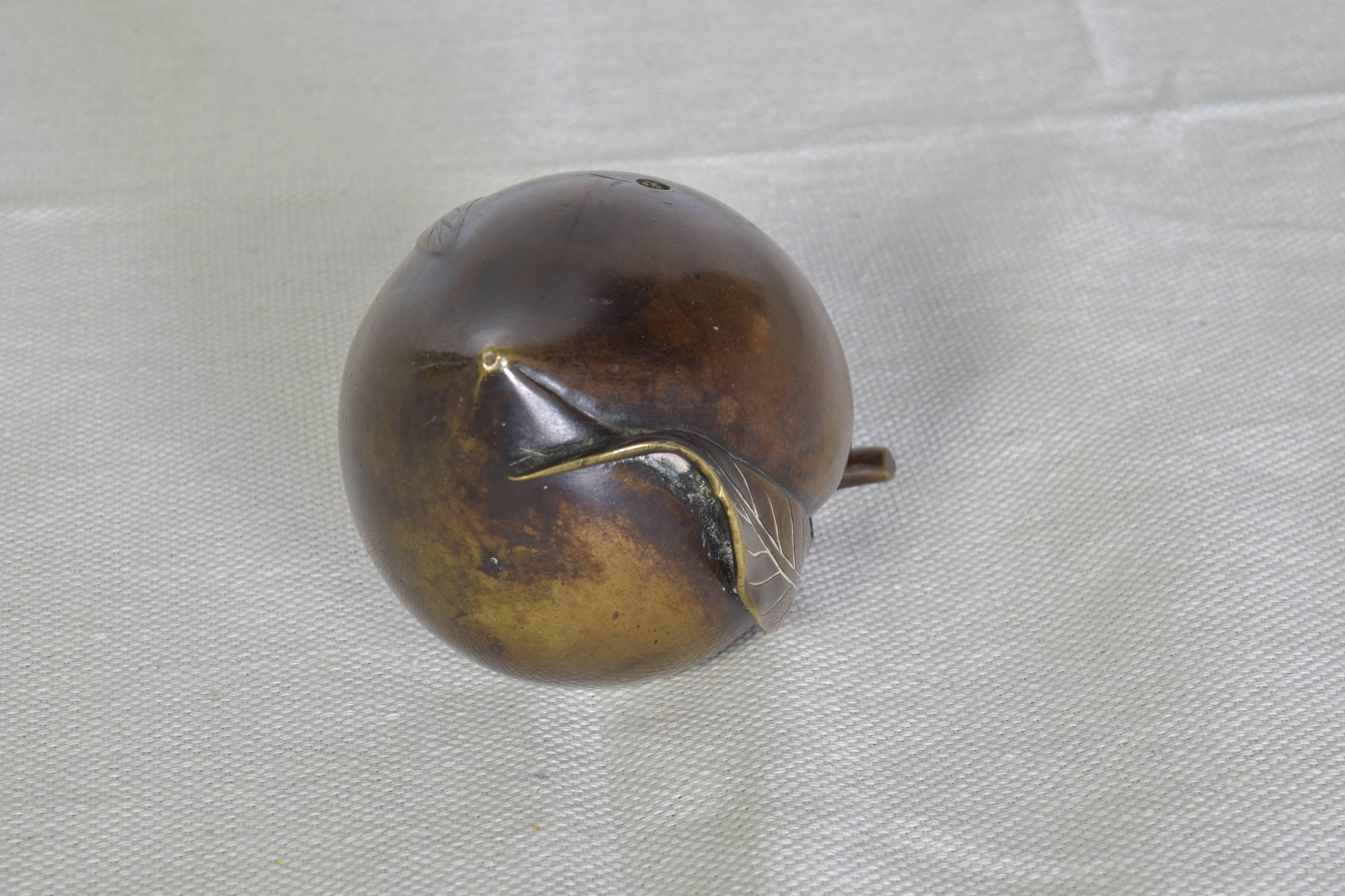 Charming bronze sculpture of a plum with stem and leaf.