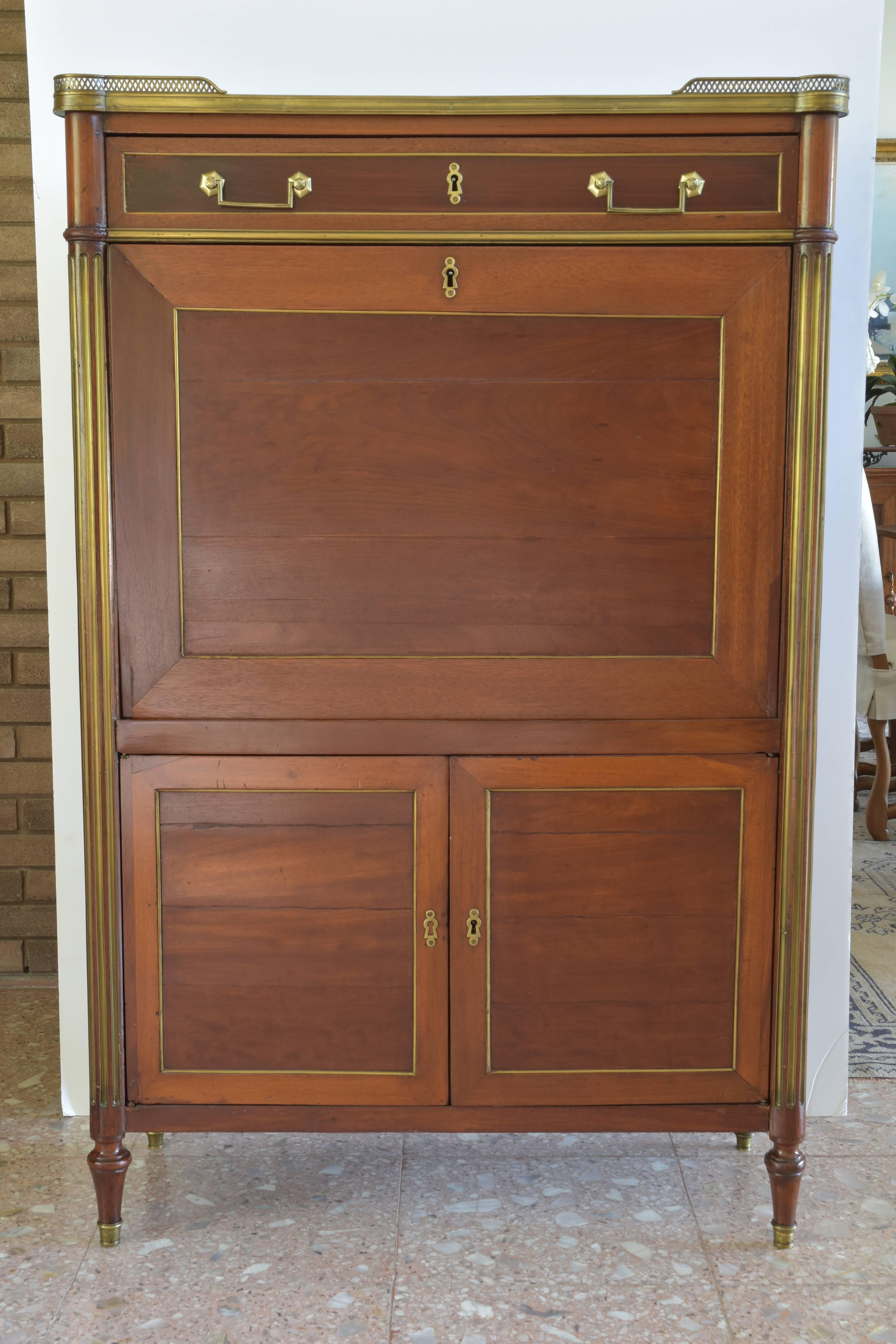 Elegant and highly functional French drop front mahogany secretary with original leather writing surface. This piece features a finely detailed bronze gallery with an inset marble top and a single drawer above the drop front desk. The interior is
