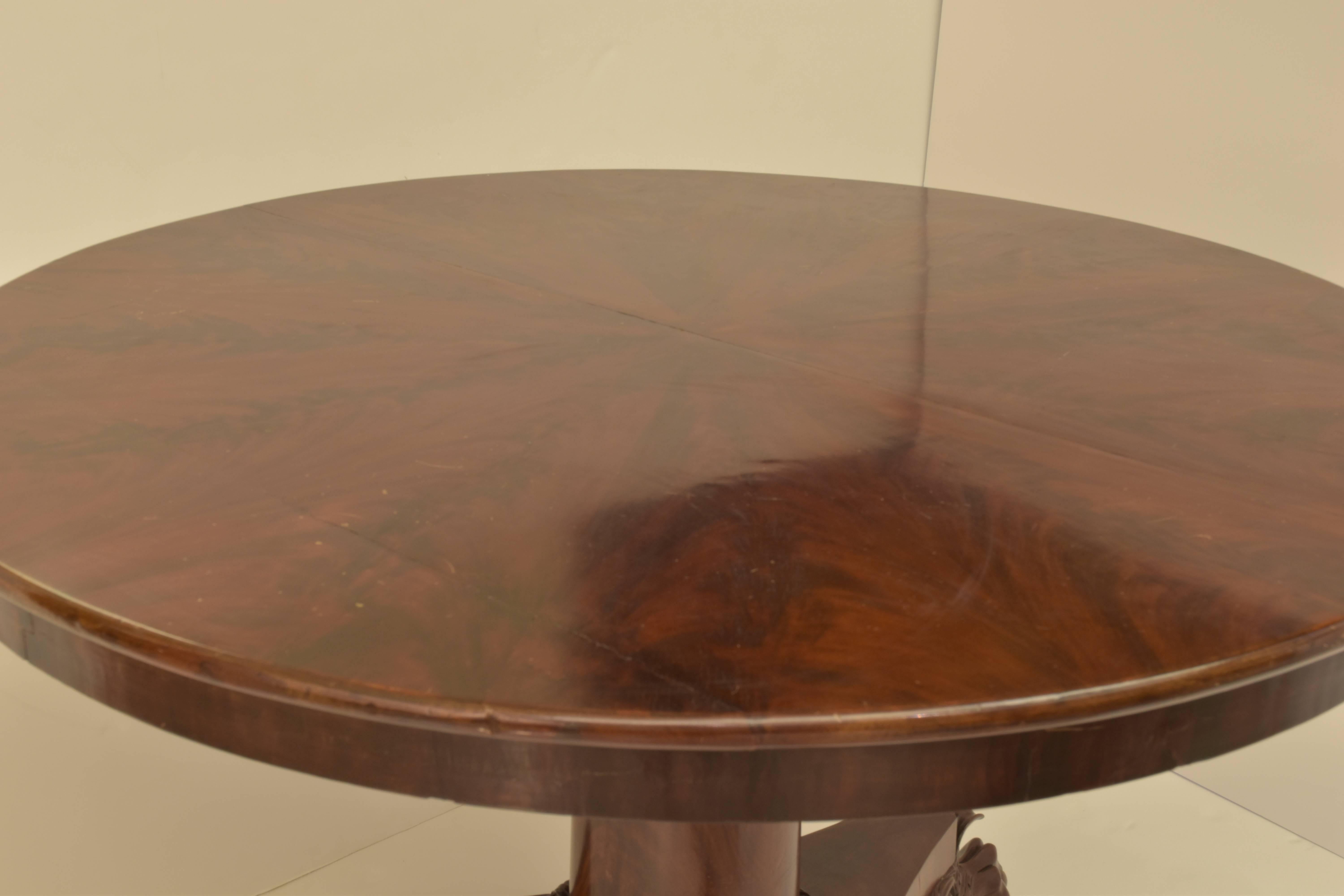 Round pedestal center table in mahogany on a tripod base with lion paw feet.
