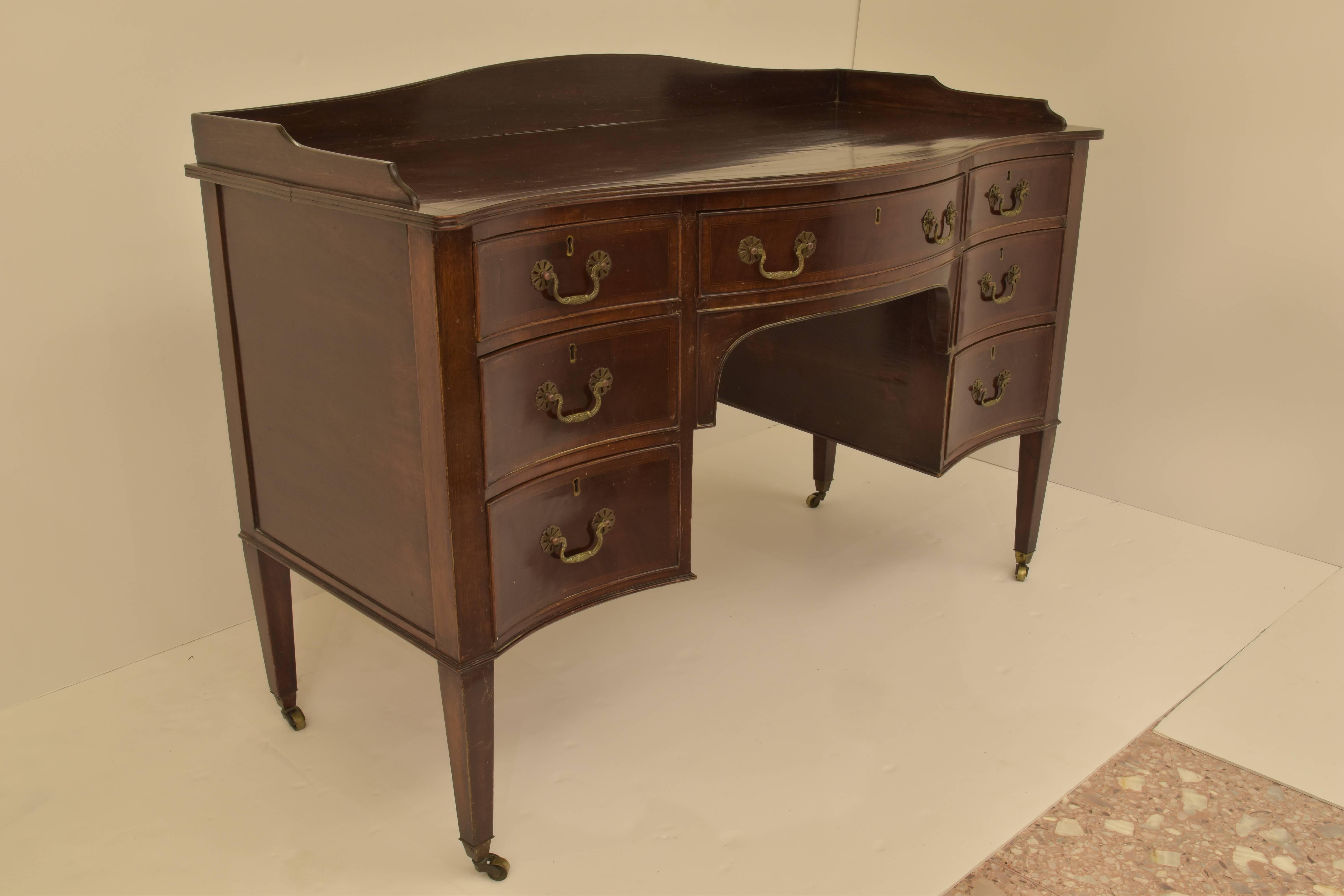 A mahogany ladies writing desk with seven drawers on brass castors.