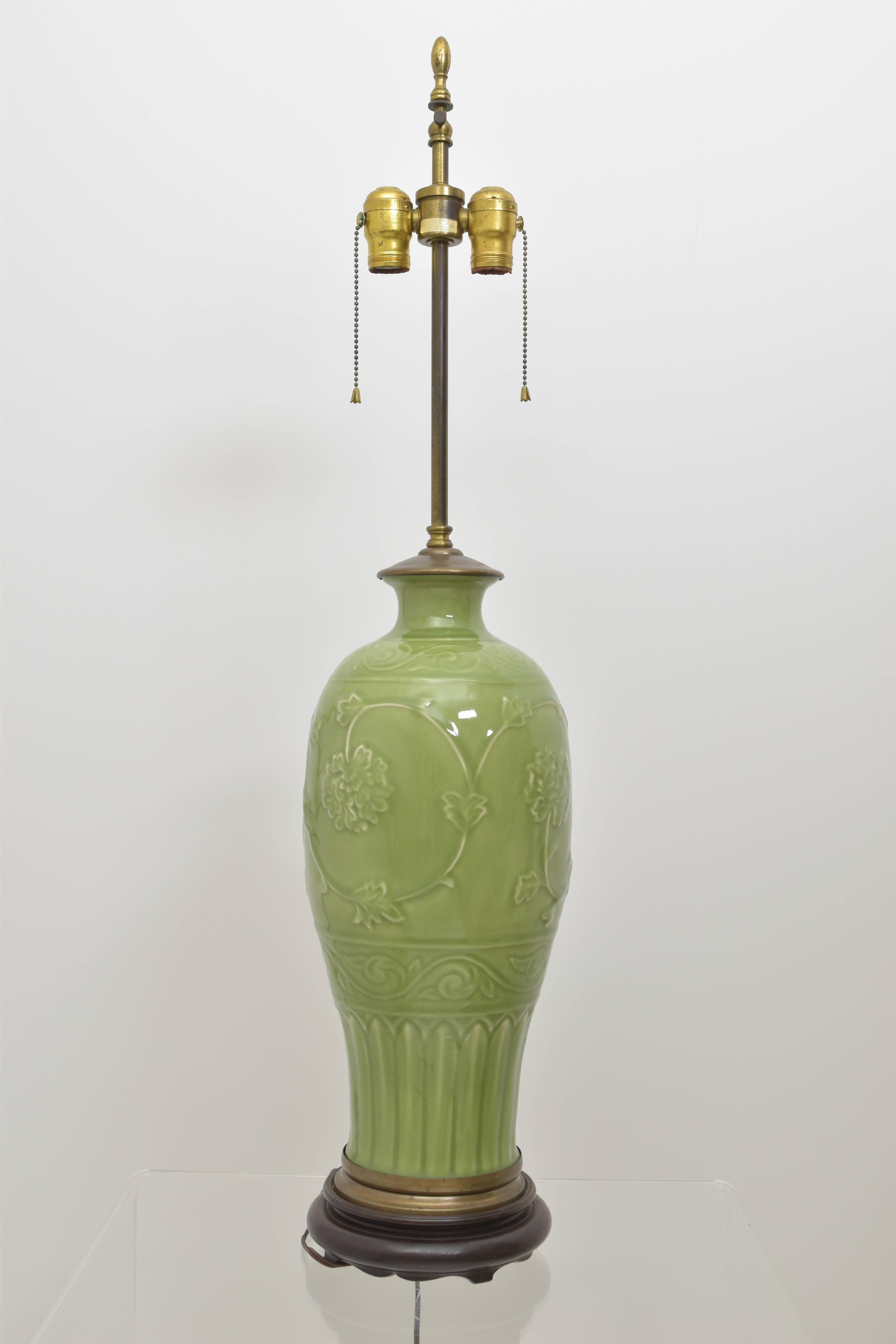 Slender celadon vase mounted on a wooden base with brass accent. Chrysanthemum detail throughout in a beautiful celadon green.