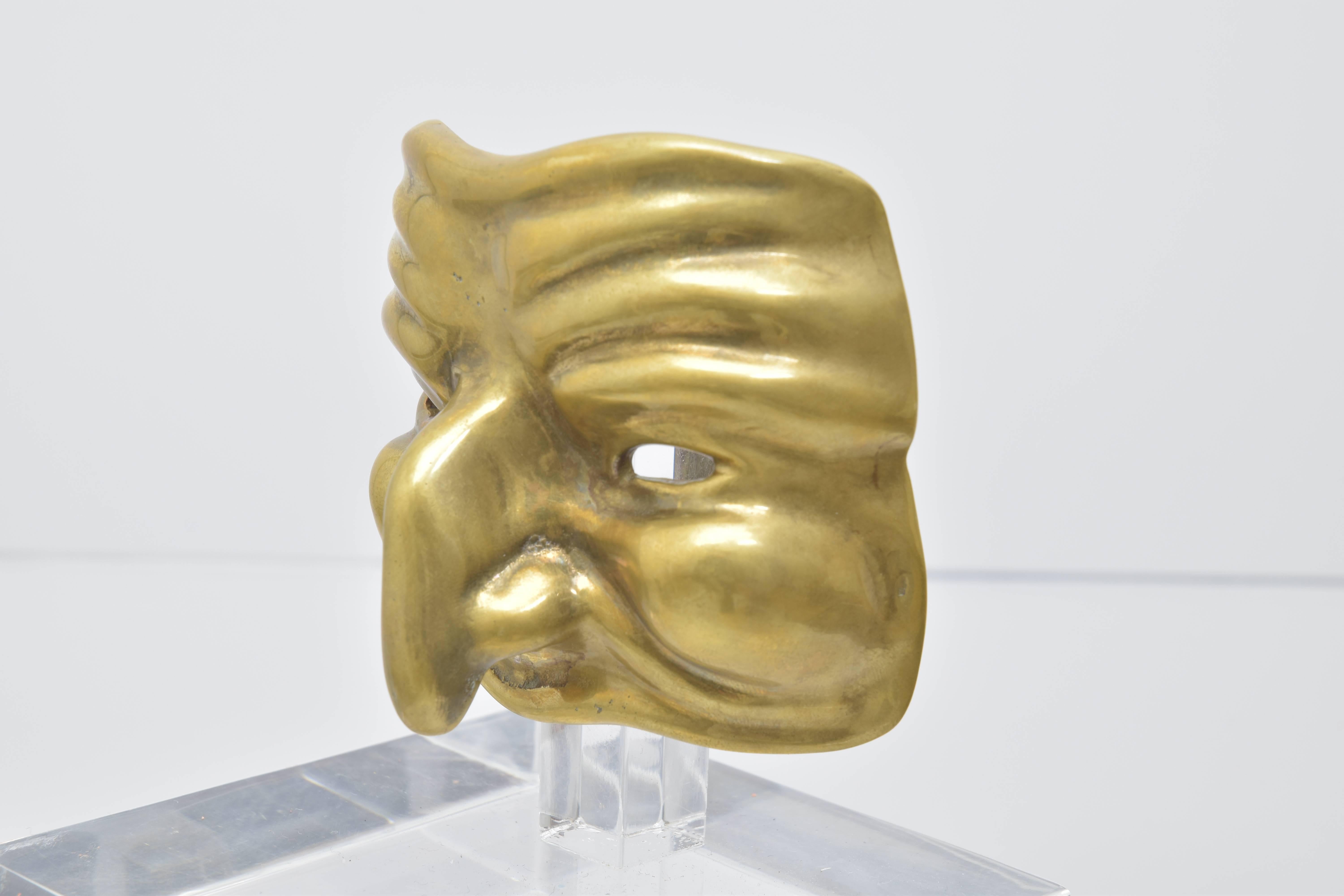 Two mounted brass theatre mask sculptures on Lucite bases.