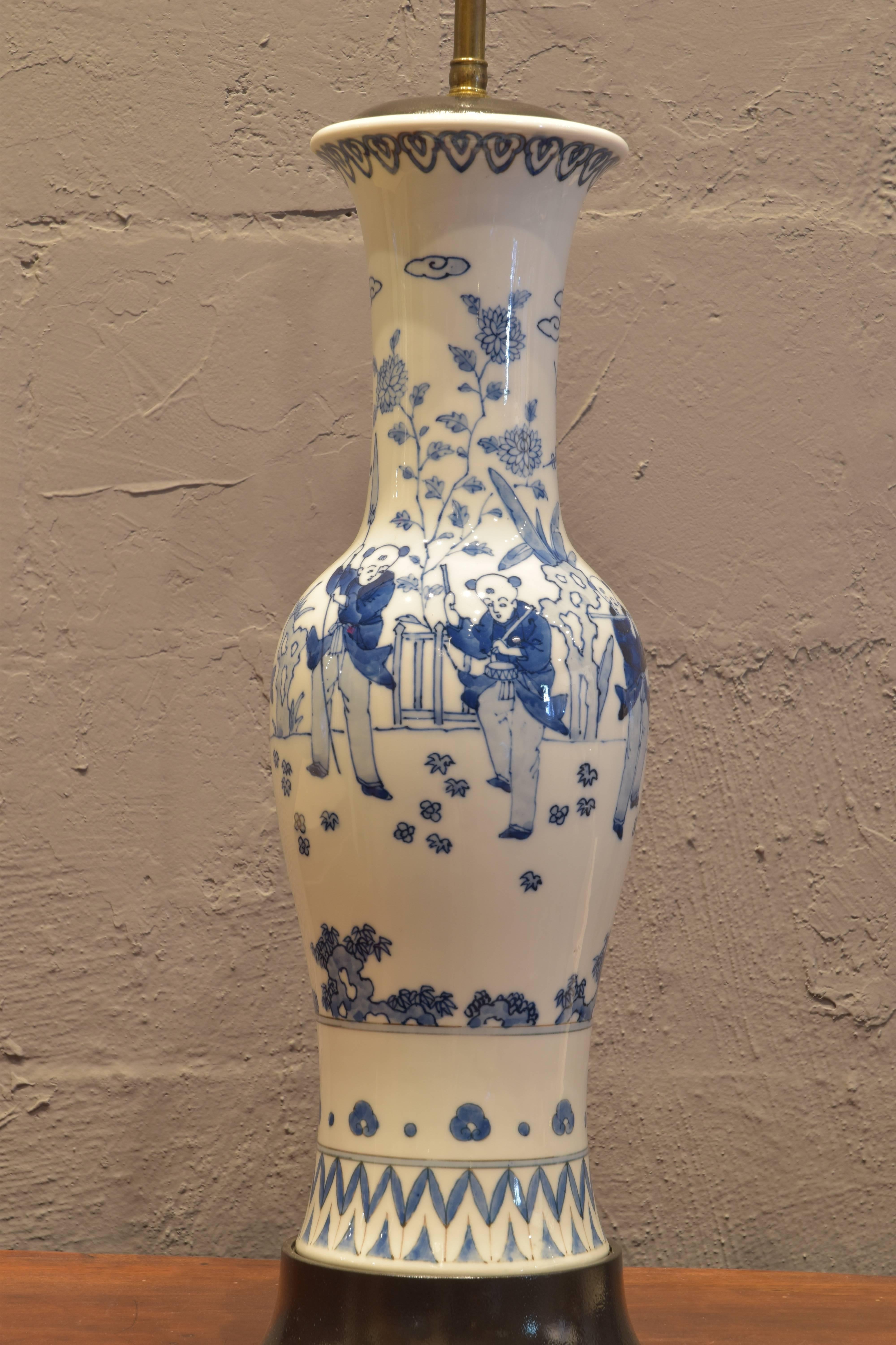Tall, slender Chinese porcelain lamp with hand-painted figural scenes on original painted black wooden base.