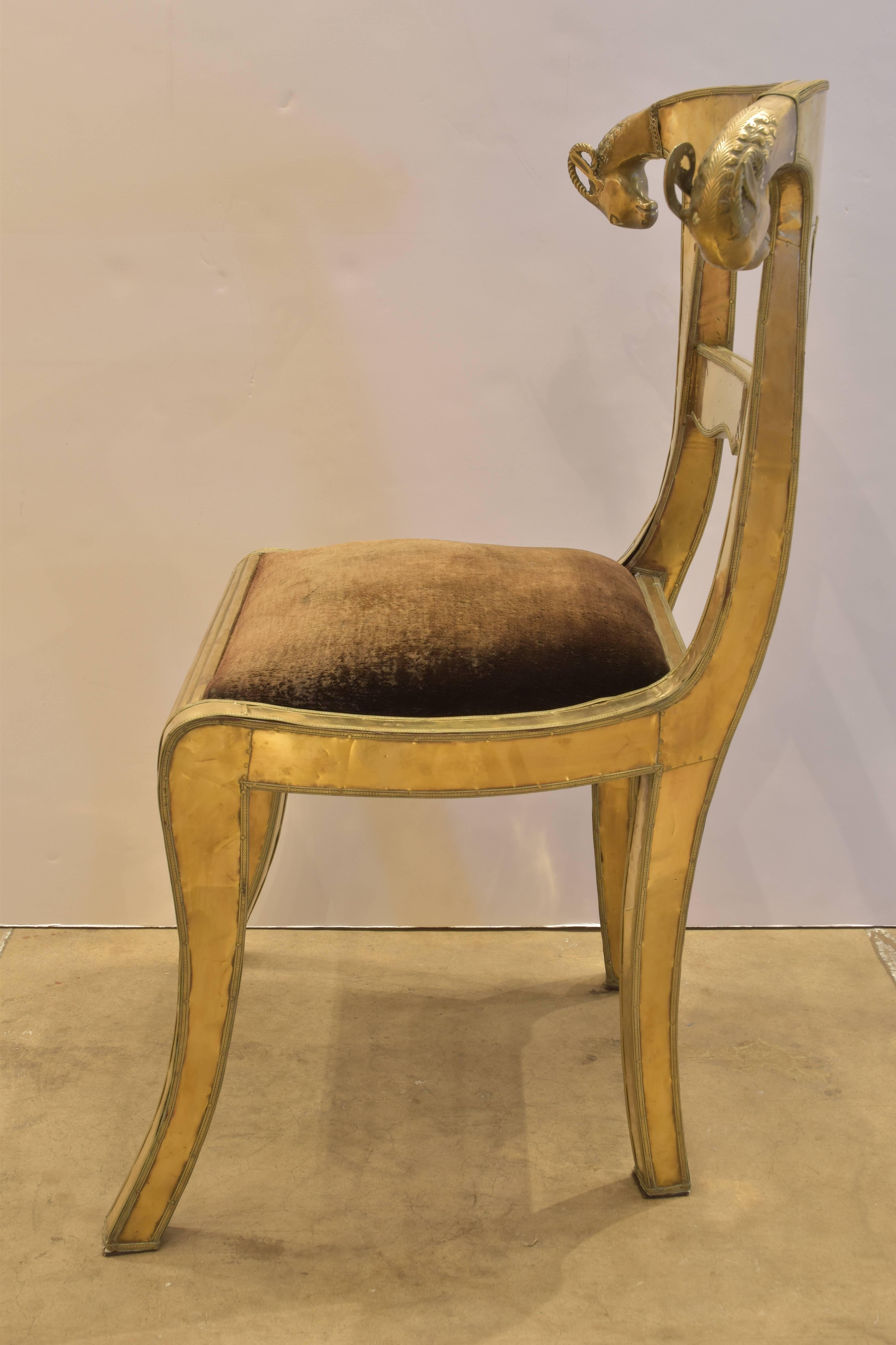 An exceptionally detailed unlacquered brass dowry chair with ram's head detail and gently tapered legs. A striking chair with vintage mohair upholstered seat.