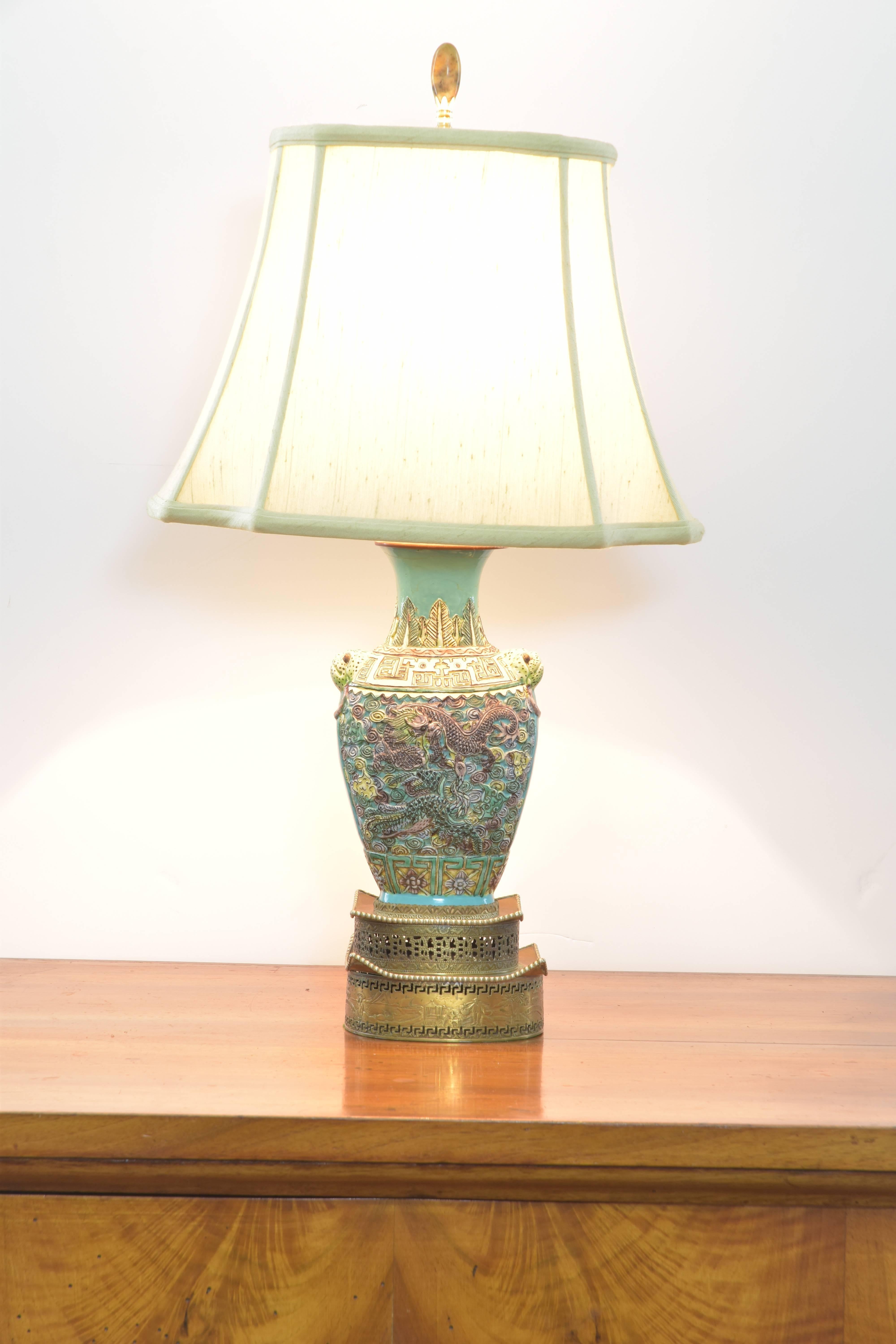 Lovely Chinese porcelain lamp in shades of aqua and pale green on a vintage pagoda form two-tiered brass base. The vase portion of the lamp features dragons and frog-like creatures as handles. The lamp was made in the mid-20th century and the vase