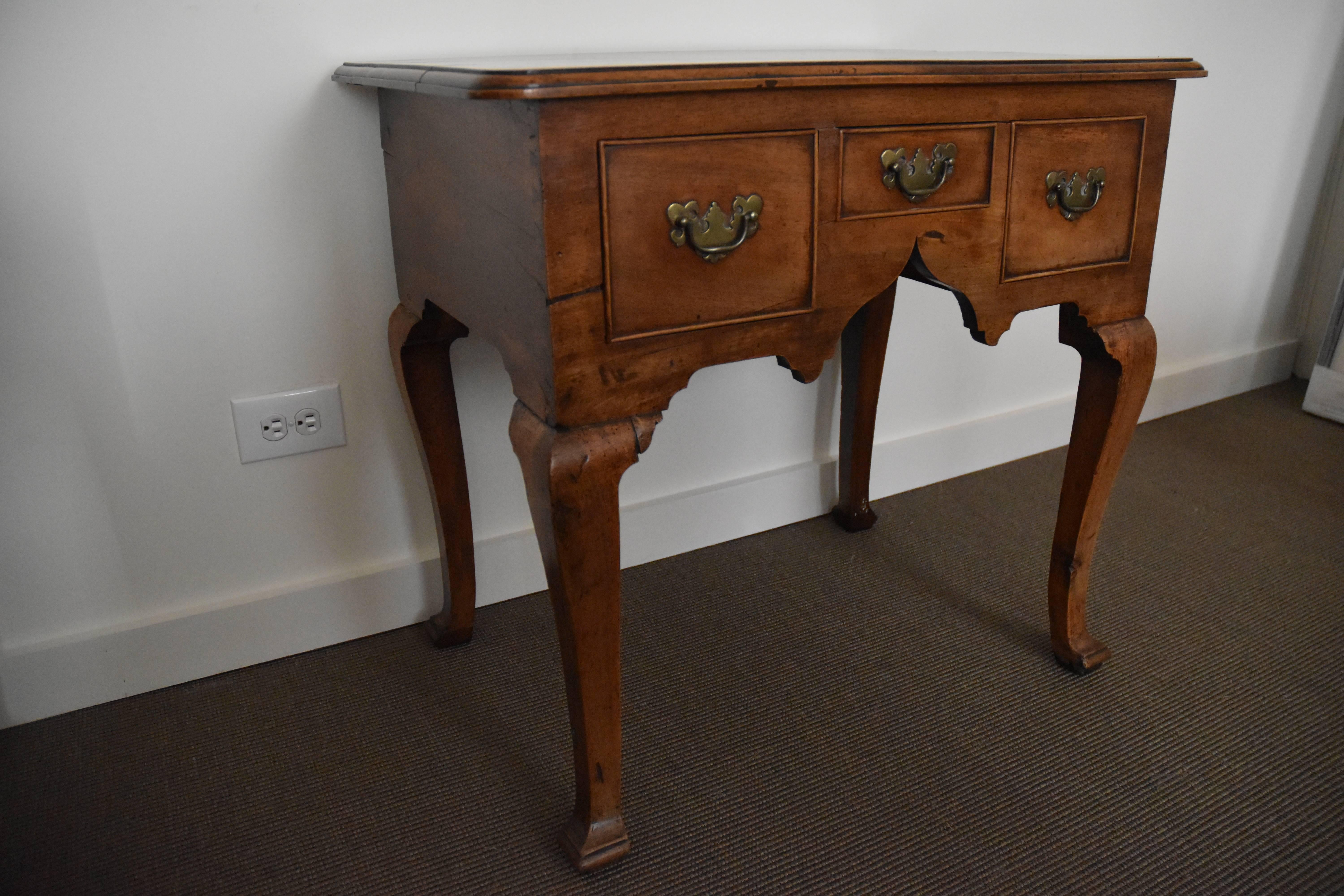 A lovely period Queen Anne lowboy on tapered legs with original brasses. The piece has a French polish and retains original brasses.