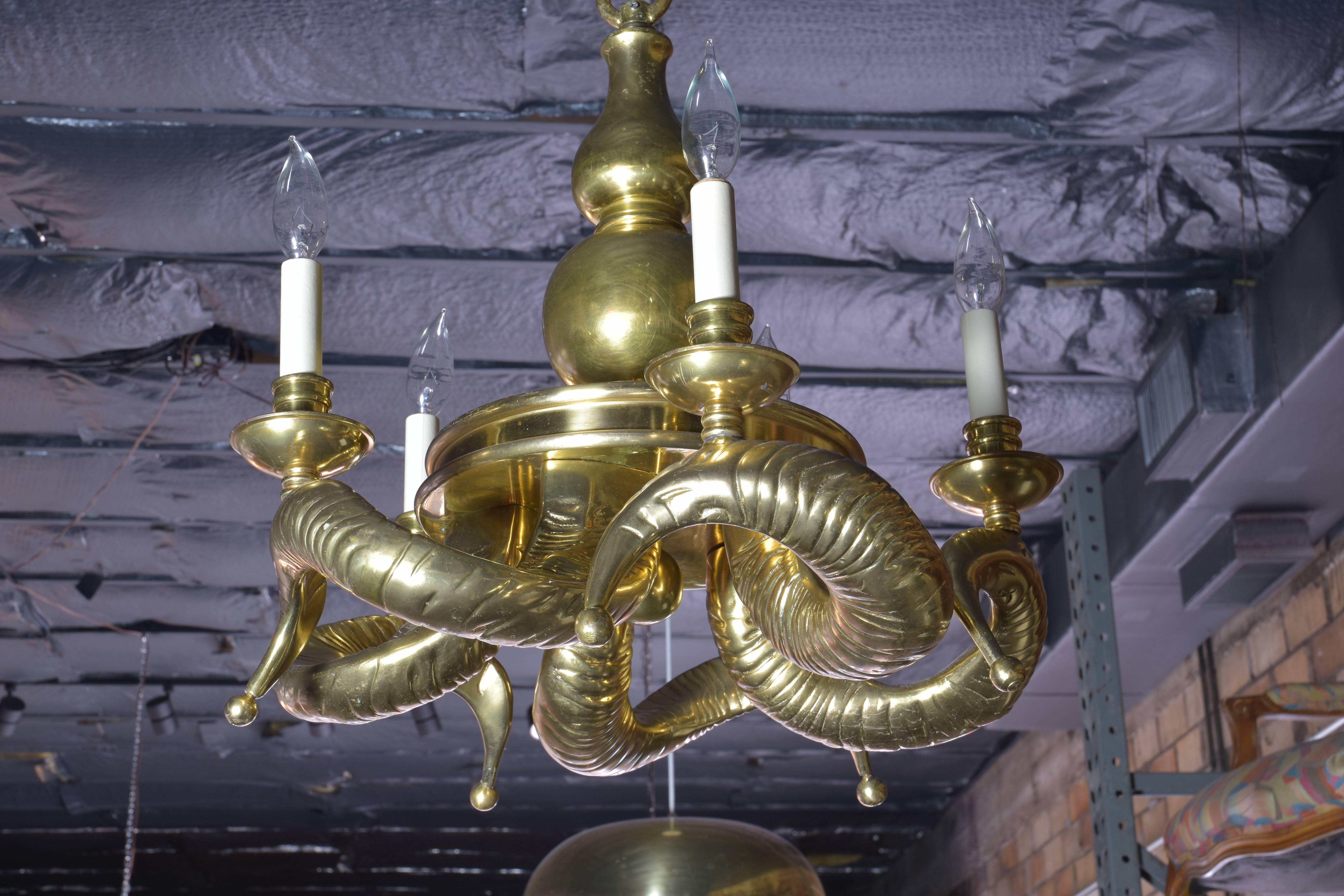 Handsome brass horn chandelier. Exceptionally heavy and quite striking with six curved ram's horn brass arms ending in a brass ball detail.