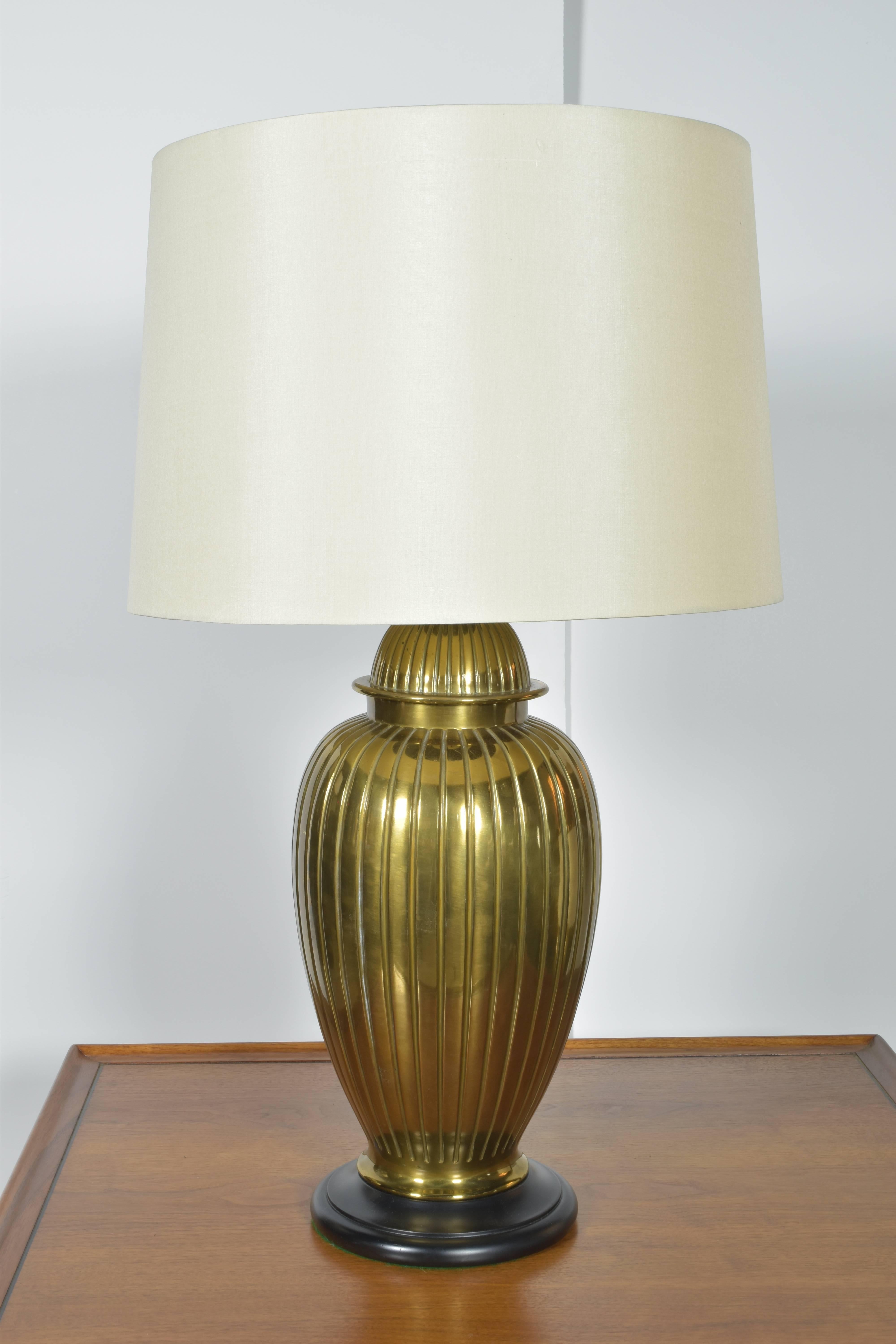 Large pair of brass urn form lamps on wooden bases.