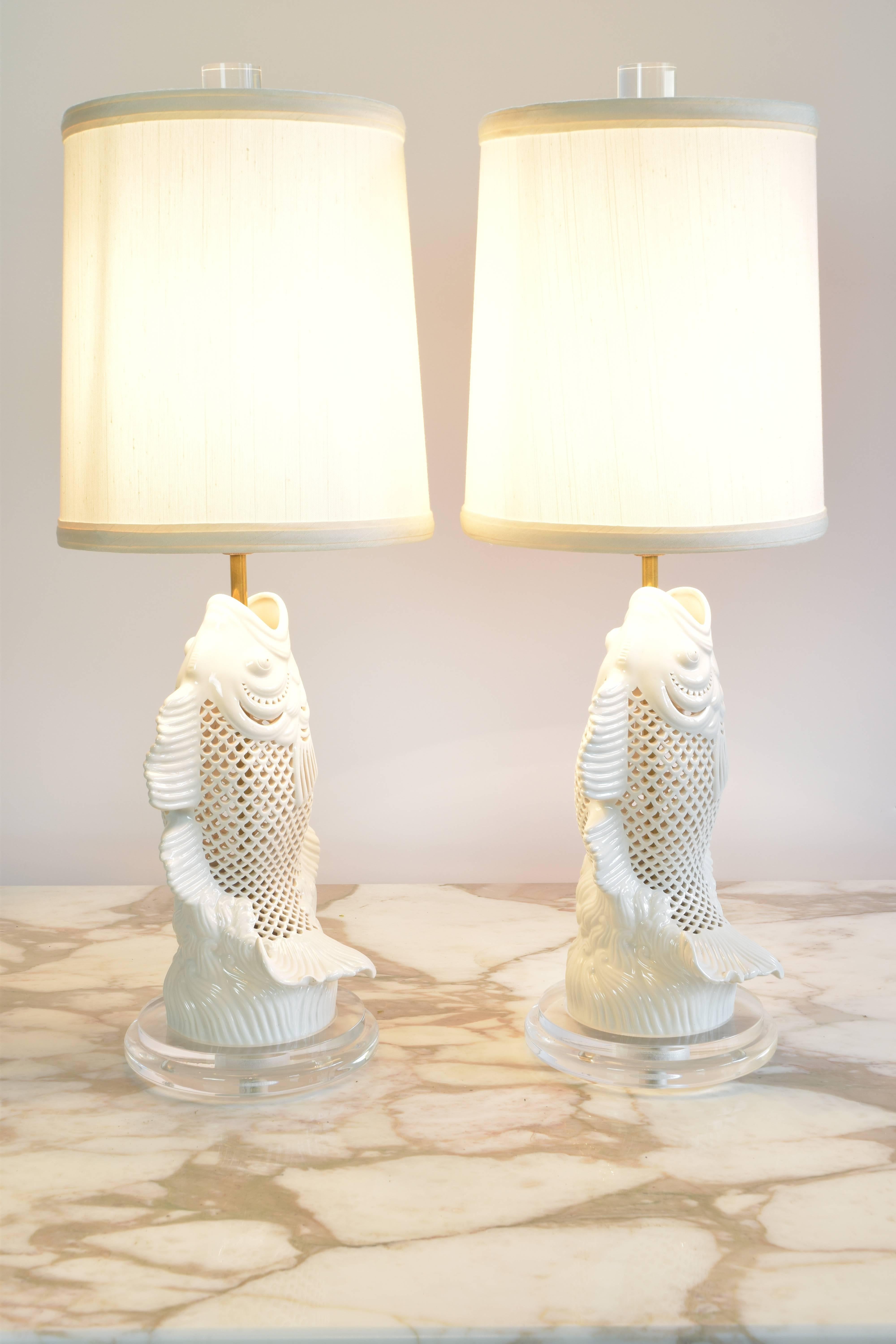 Charming pair of Chinese pierced porcelain vases in the shape of fish wired as lamps. So charming with their upturned tables and beautiful wave details at the base. Newly wired on acrylic bases with silk drum shades and Lucite finials.