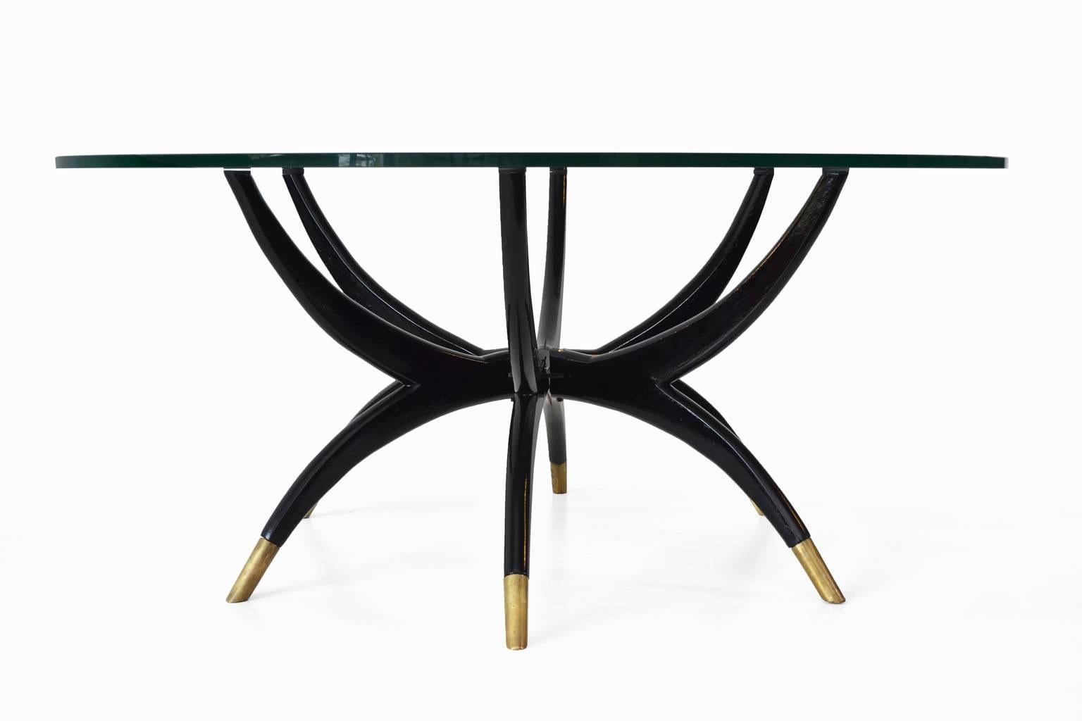Stunning spider leg coffee table, 1950s. Beautiful organic and elegant form. High gloss black wooden base with graceful brass sockets, on top a 12 mm thick glass plate. Nice decorative and luxurious Mid-Century Modern piece. All in excellent