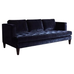 Canapé en velours bleu nuit à accoudoirs arrondis, avec assise capitonnée de boutons en forme de losange