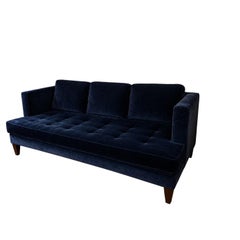 Canapé en velours bleu nuit à accoudoirs arrondis, avec assise capitonnée de boutons en forme de losange