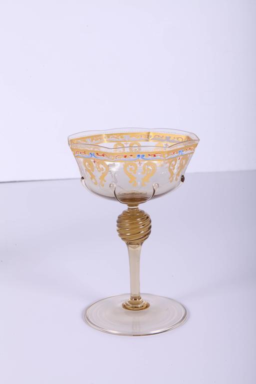 Regal 55 piece table stemware and dessert service in gilt and enameled pale topaz colored Murano glass comprising (13) octagonal wines or water glasses, (14) octagonal champagne glasses, (14) round dessert plates and (14) octagonal dessert or finger