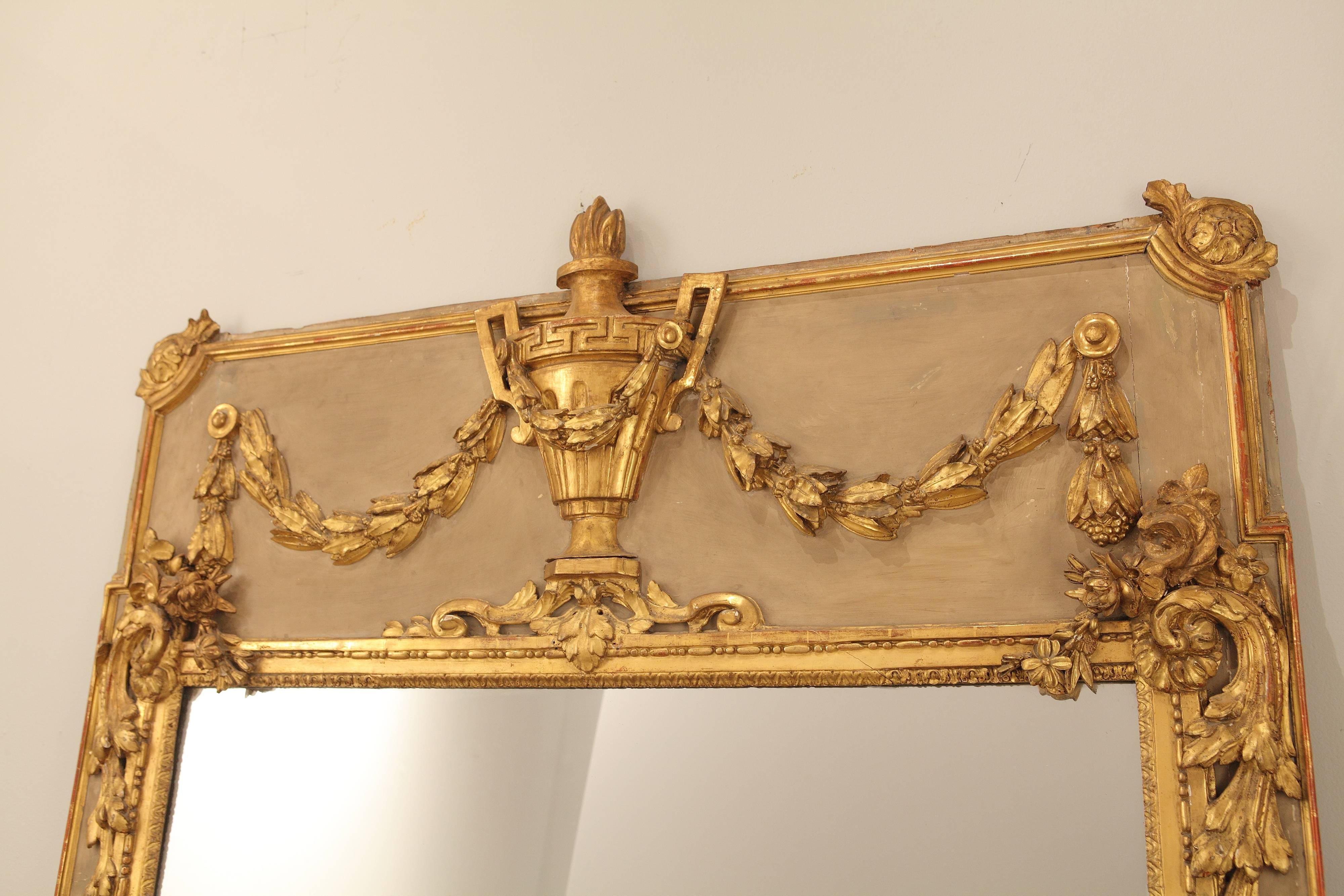 Exquisite painted and water gilt 19th century Louis XVI style mirror with leaf and flower swags centering a handsome Greek key banded and flame topped urn.

 