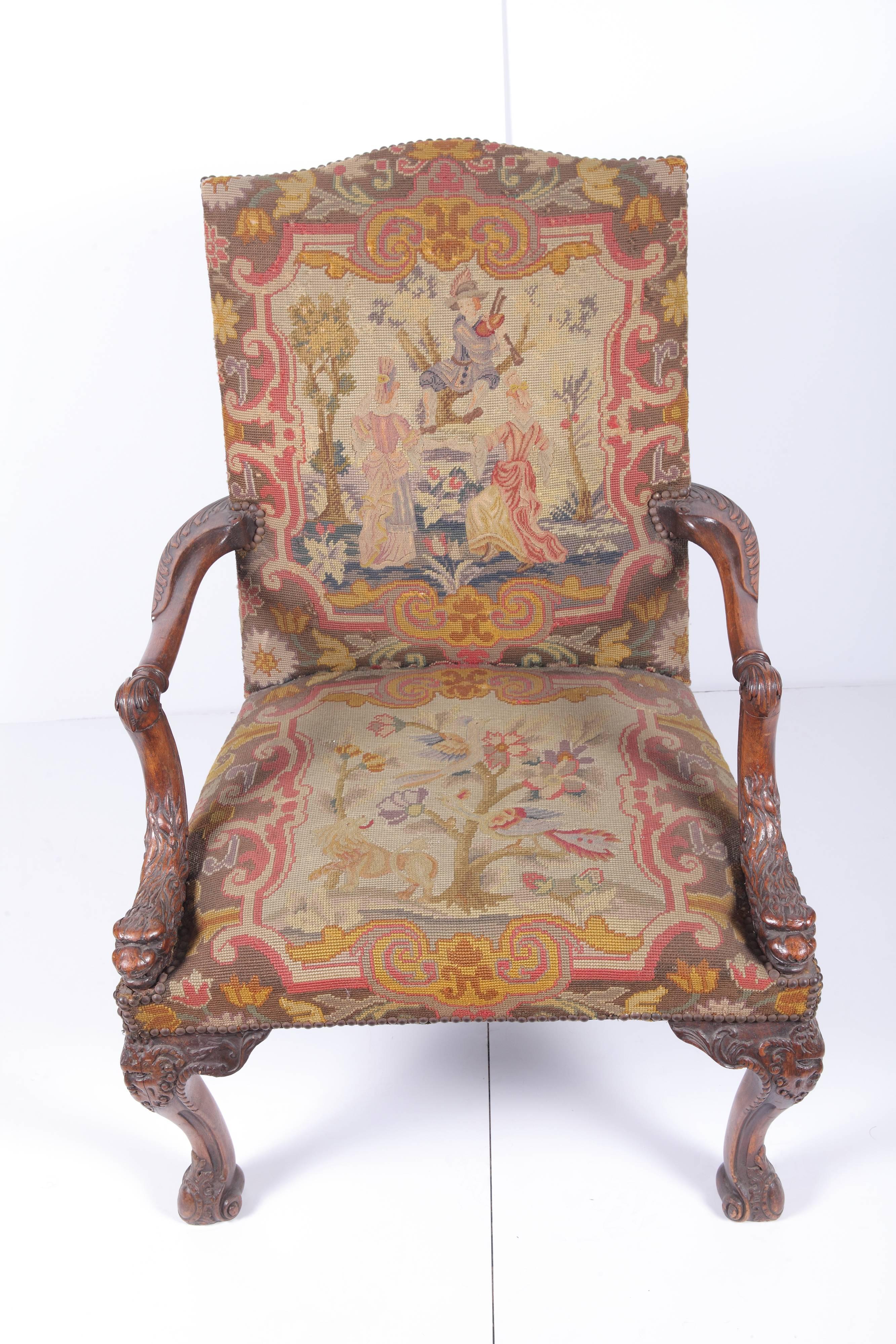 Early 19th century Gainsborough style armchair having serpentine-topped upholstered back and lion's head carved set-back arms above a seat supported on carved cabriole legs with masks on the knees.