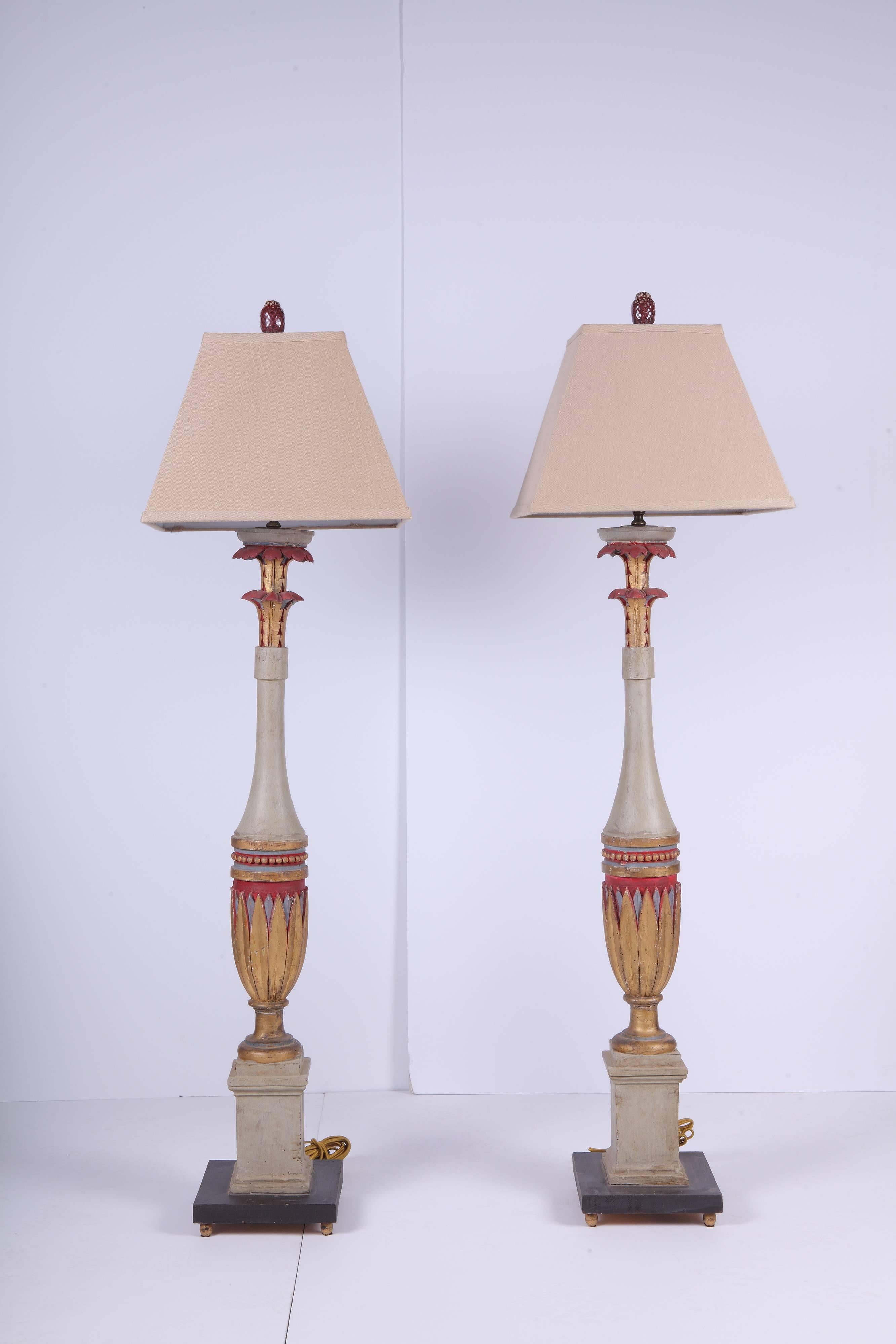 Pair of tall handsomely carved lamps with a wonderful Art Deco design painted in a cinnabar color with gilding at the top. Later black bases and gold bun feet. Good condition with normal wear for this age. New cinnabar colored ceramic finials. Very