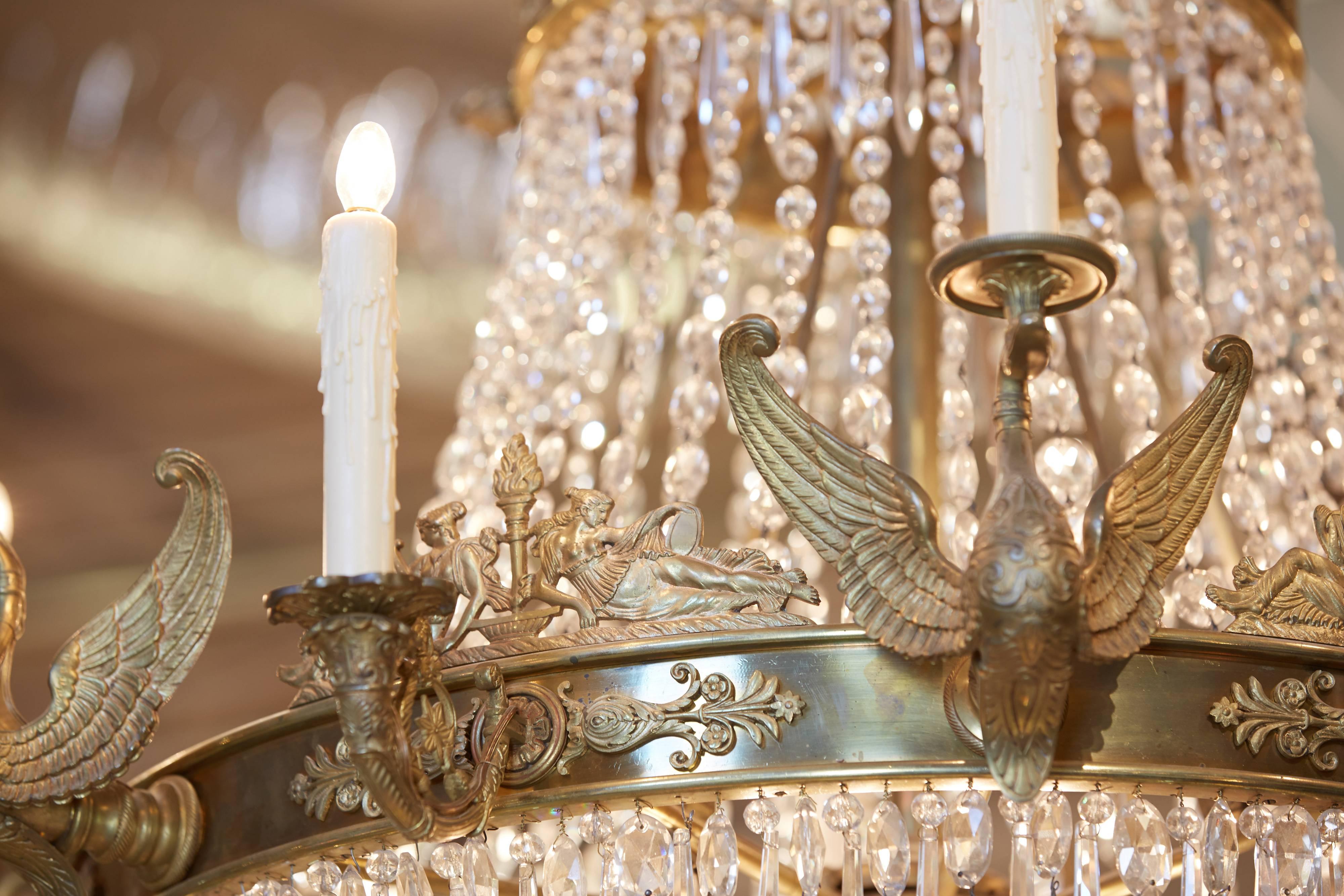 Large French Empire style chandelier in finely chased gilt bronze and hand cut crystal. 12 exterior lighted candles and eight interior fittings for chandelier sized bulbs.