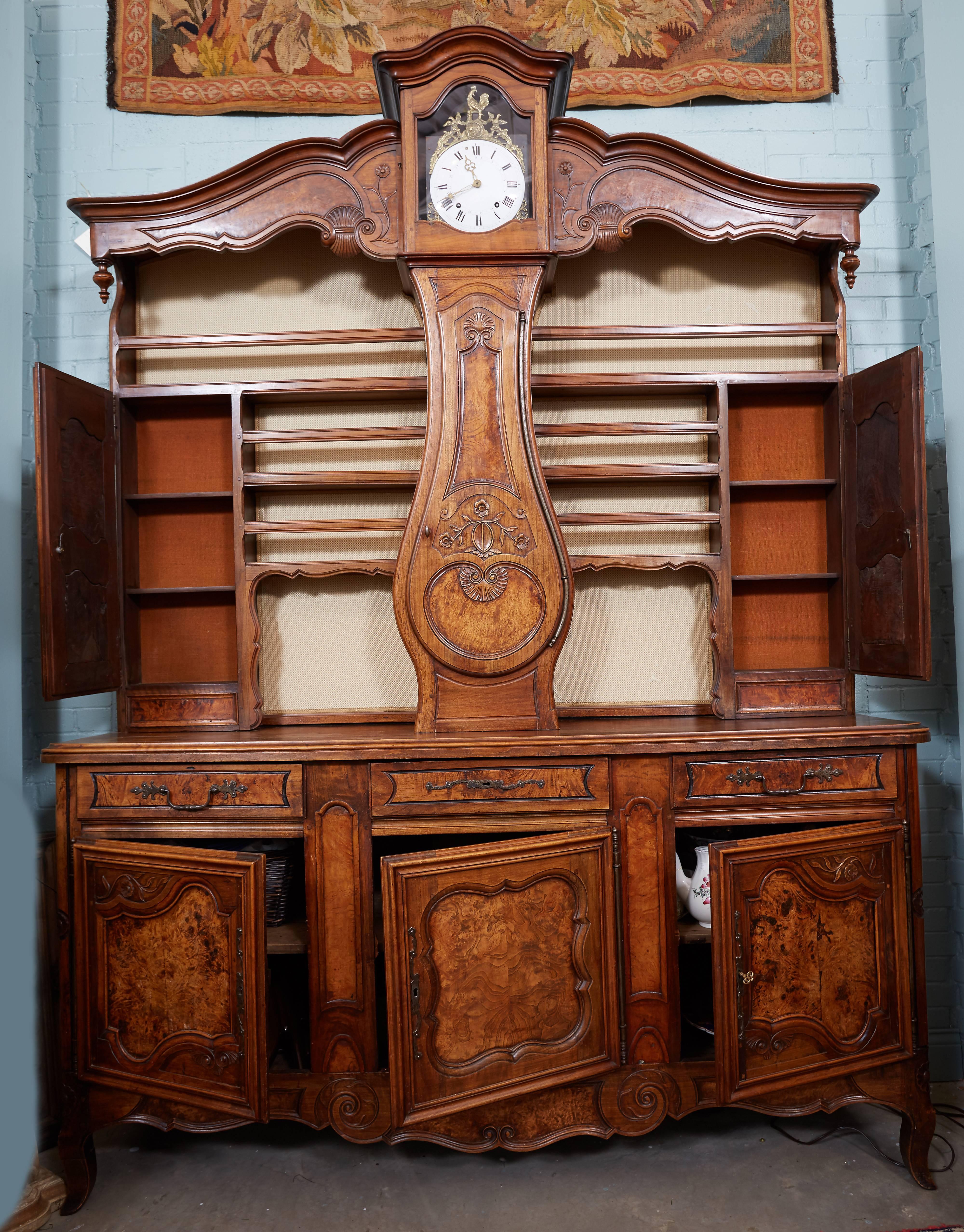 19th century clock vasselier from Lyon. Handsomely carved and patinated walnut. Three working drawers and ample storage compartments. Clock is in good working condition.