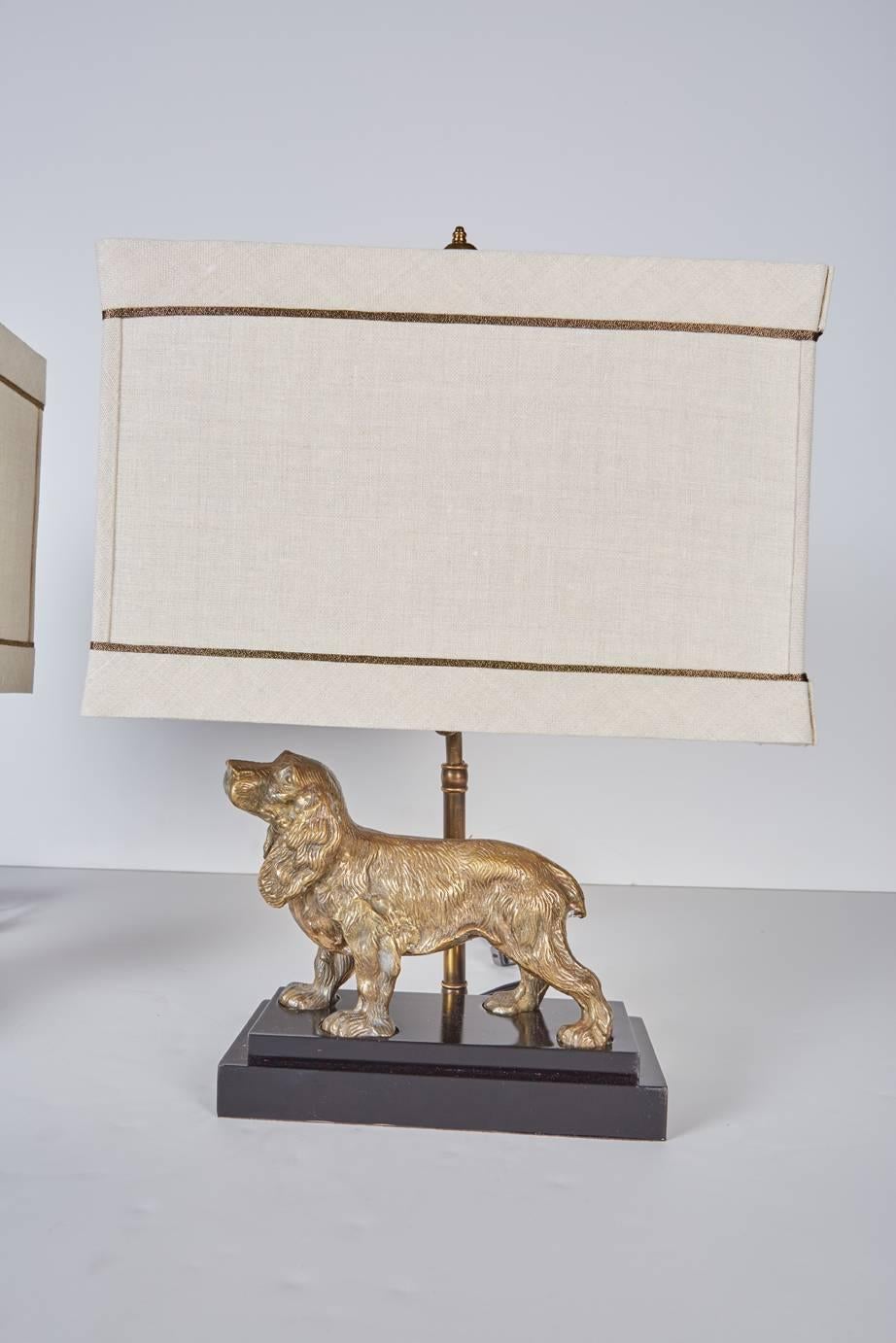 Pair of vintage brass spaniels mounted as lamps on custom, black lacquered bases with custom beige linen shades trimmed in antiqued gold cord.