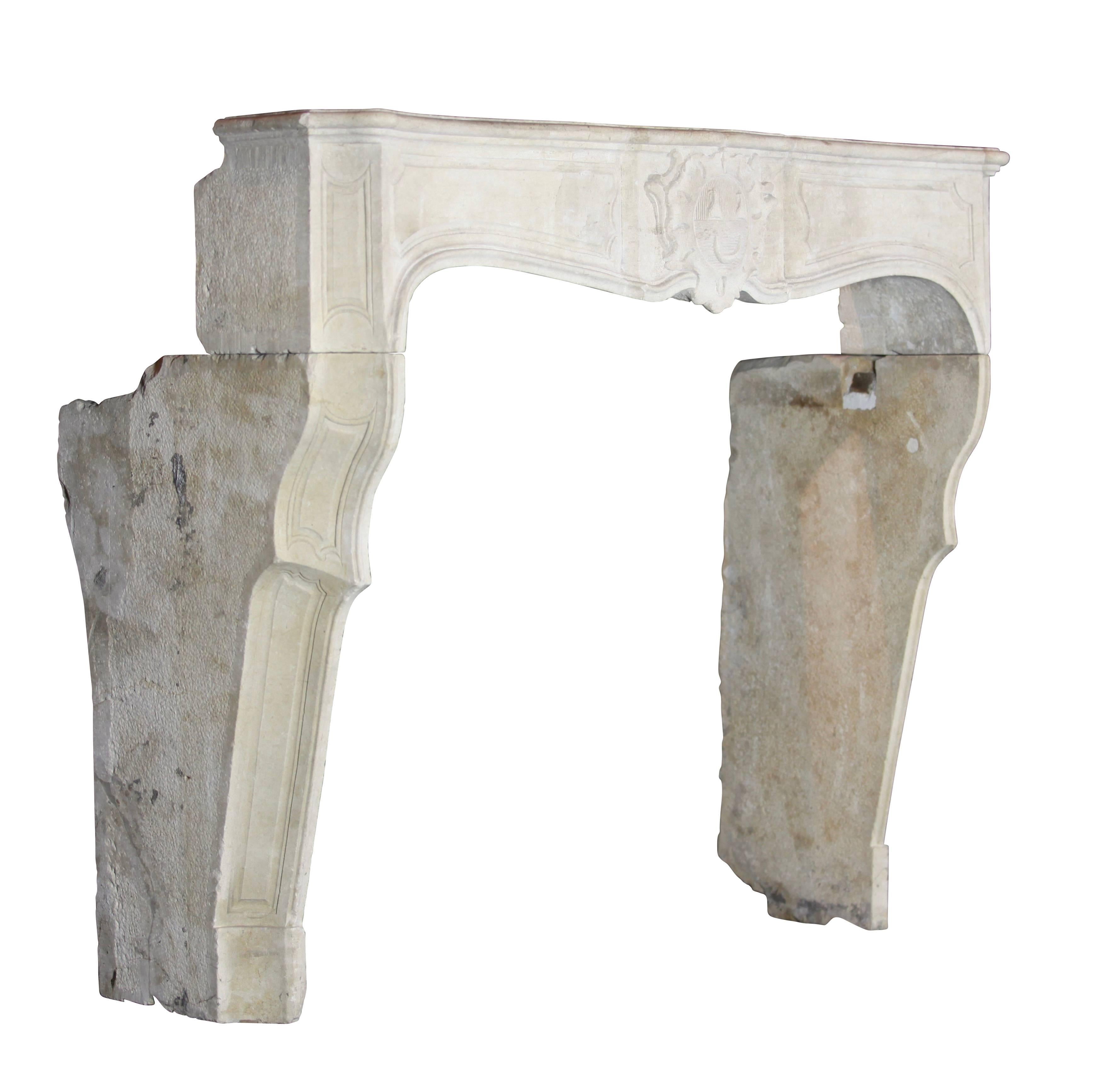 This again is a fabulous original antique fireplace surround in limestone. The central cartouche on the front holds a family crest of a nobilli. The movement in the jambs brings an extra elegancy to it. A perfect match for a small firebox. This