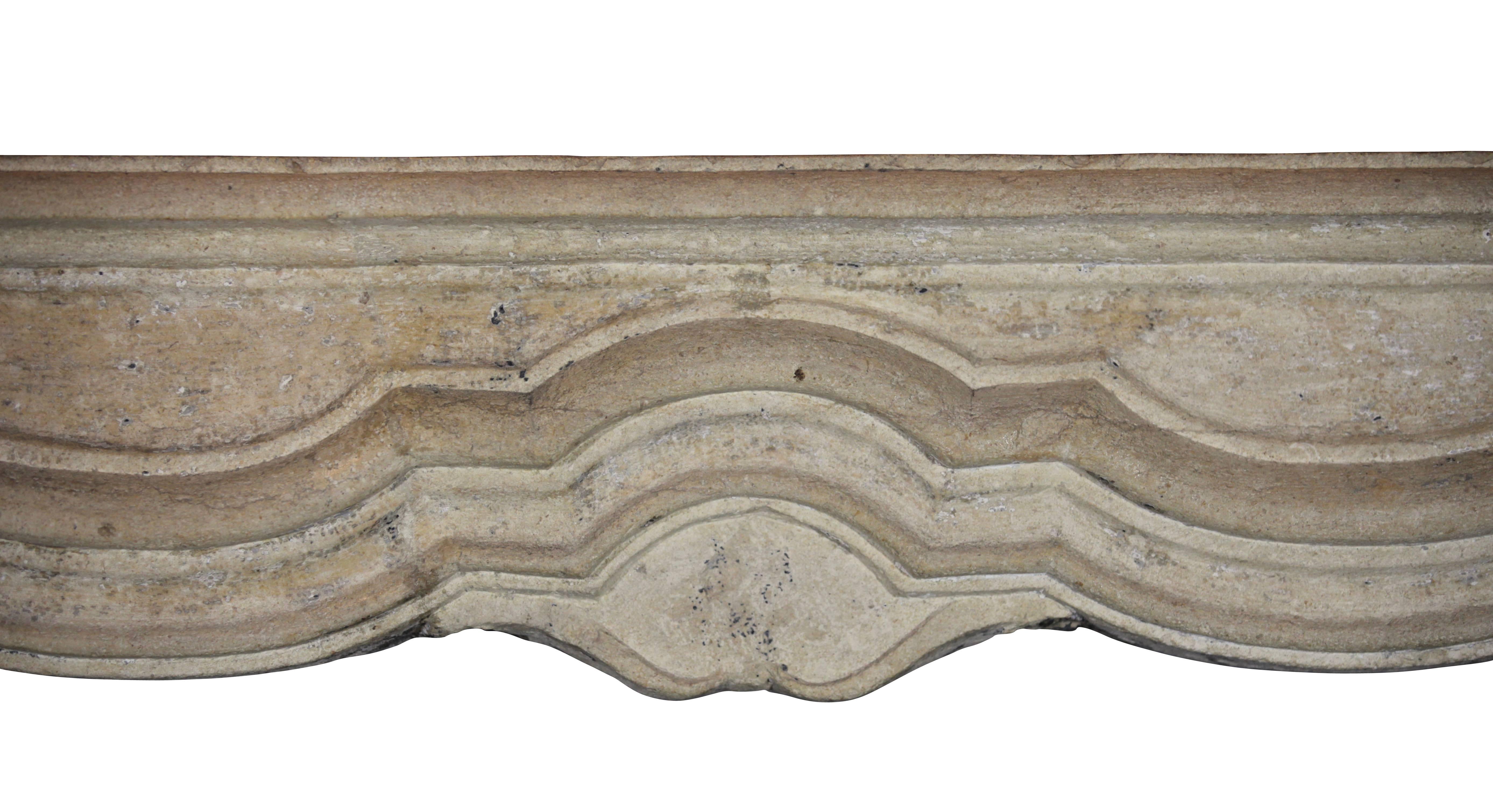 This is a wide, large, limestone antique French fireplace surround. The floral details of the carving is quite easy on the eye. The quality of the limestone is high. The ancient surfaces has been waxed. This French rustic fireplace reflects the