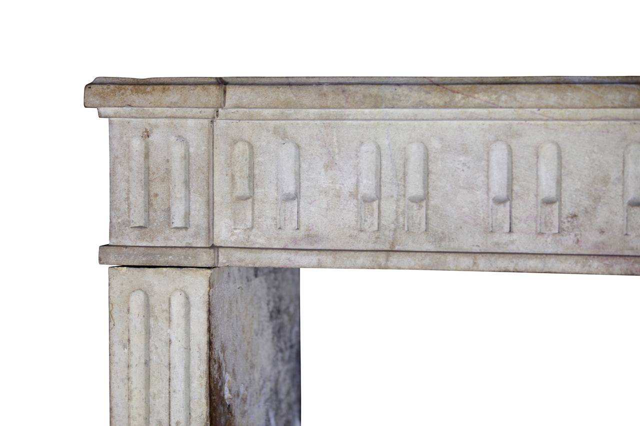 This is a Louis XVI period original fireplace surround in Burgundy hard limestone; it is from the Dijon region in France. It is composed of three solid blocks and it is in great condition. One would call it a classic French limestone fireplace. The