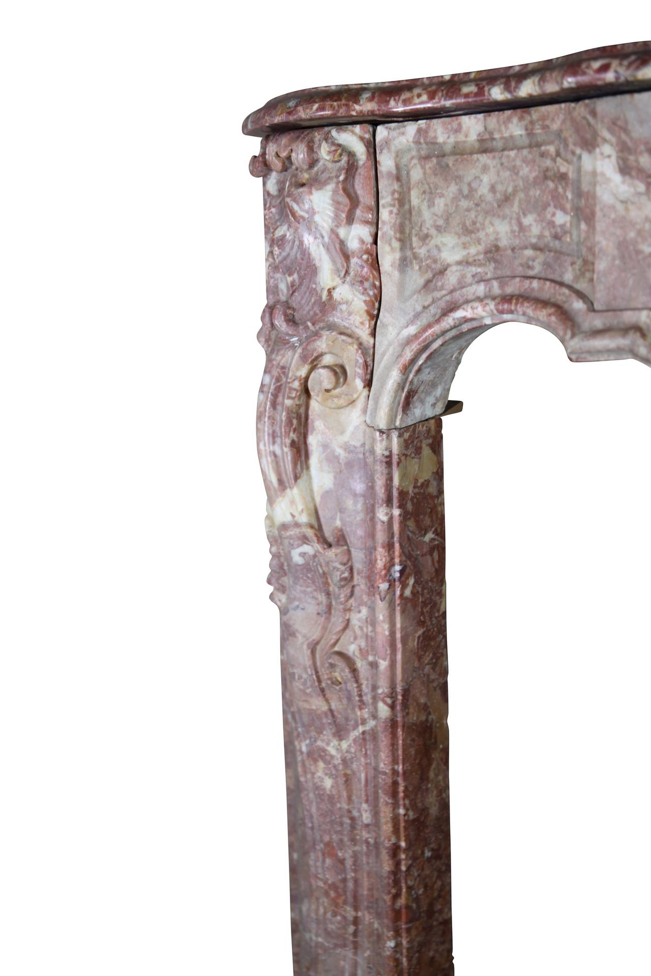 This color full original antique fireplace surround has an arbalette design on the fronton. It was crafted during the Regency Period. The front is a solid block of marble. The rich carving on the mantel is very decorative. It is from Florence. The